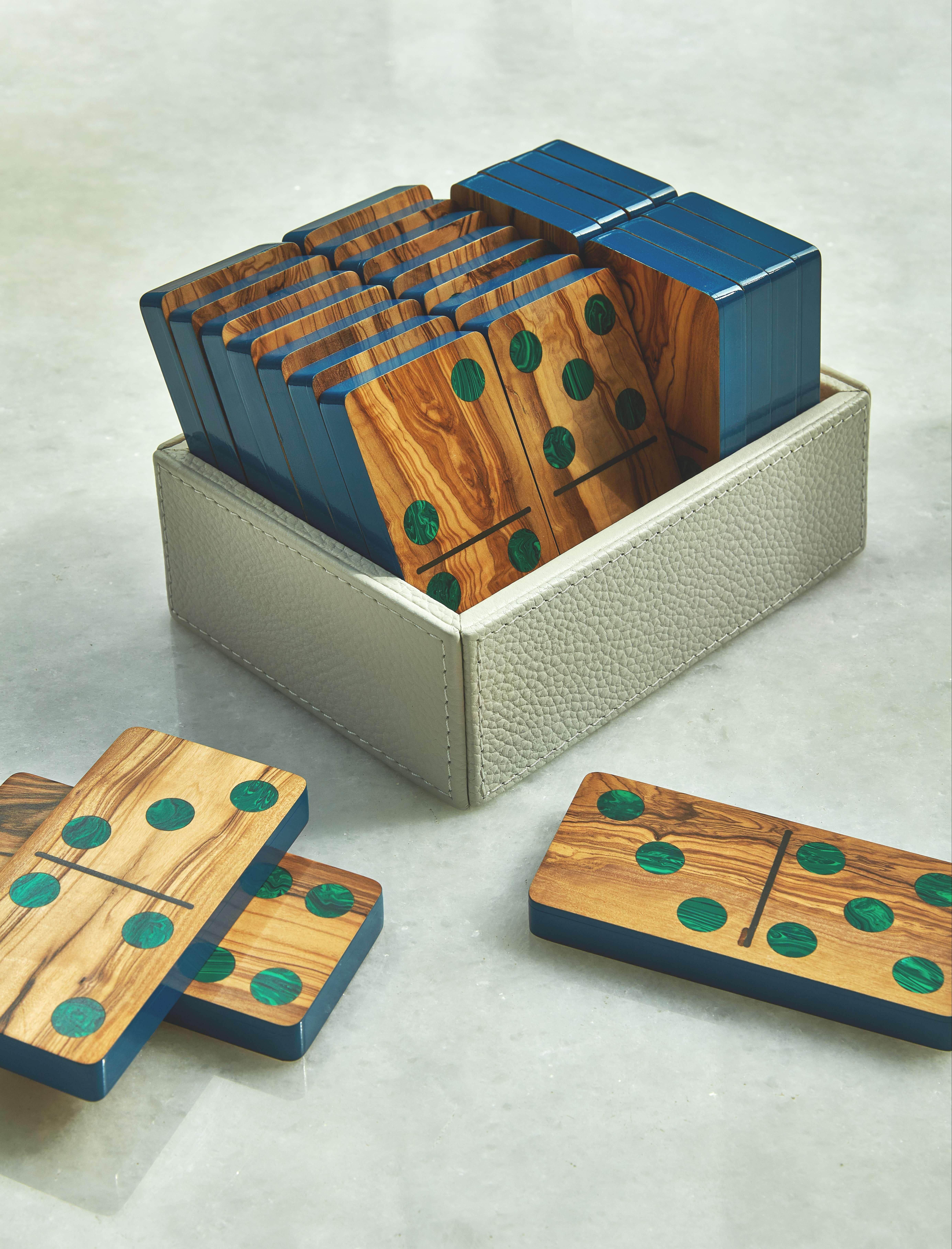Our large Domino set is composed of 28 pieces of olive wood with malachite inlay. Each piece is outlined in blue polyurethane paint and elegantly stored in a leather box.

Nothing better than having fun, and if you can do it in style even better.
