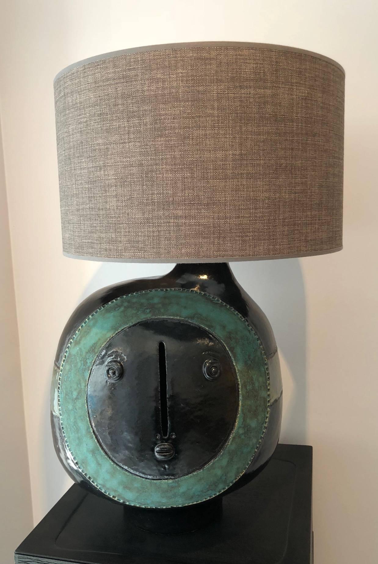 Large hand-sculpted ceramic lamp base, stoneware glazed in shiny black, decorated with two biomorphic visages sculpted and incised in green enamel and stripes on sides.

One of a kind handmade piece signed by the French ceramicists. 

The height