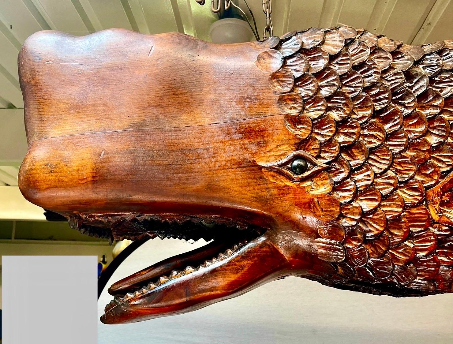 Immergi il tuo spazio nella grandezza oceanica con questo straordinario lampadario a balena in legno intagliato a mano, unico nel suo genere. Questo apparecchio di illuminazione unico combina il fascino rustico del legno intagliato a mano con la