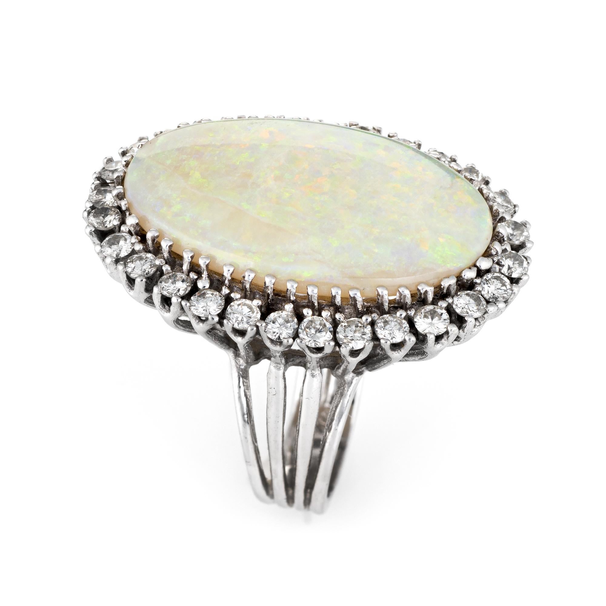 Finely detailed large vintage opal & diamond cocktail ring (circa 1960s to 1970s), crafted in 14 karat white gold. 

One cabochon cut white Opal, approx. 16.0 carats (28.0 x 18.0 x 5.5mm), moderate green/blue/yellow/orange play of color on a