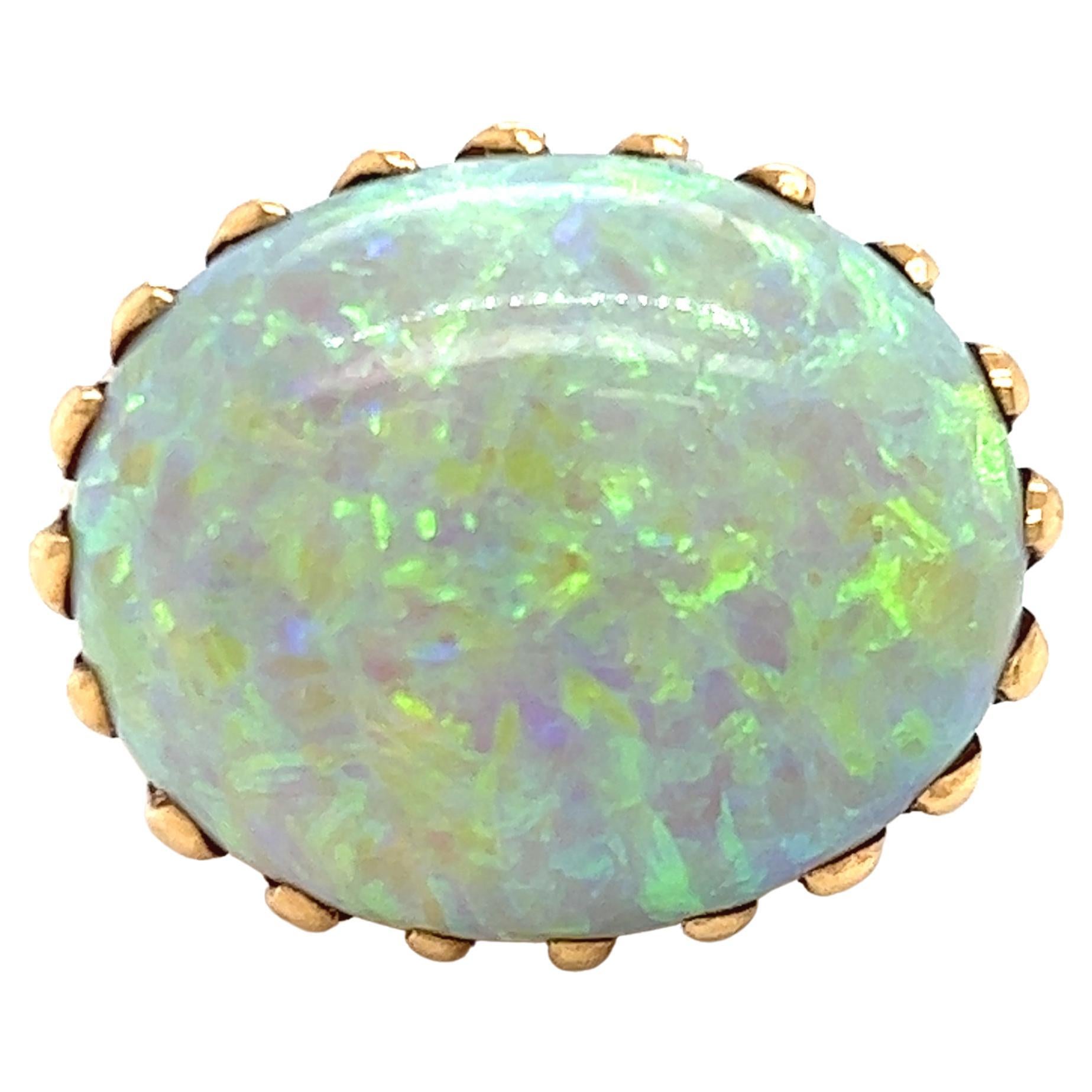 A lush 32 carat opal with striking shades of greens and purple is poised in the most exquisite setting, made of undulating waves of gold. Size 7 and can be sized. 