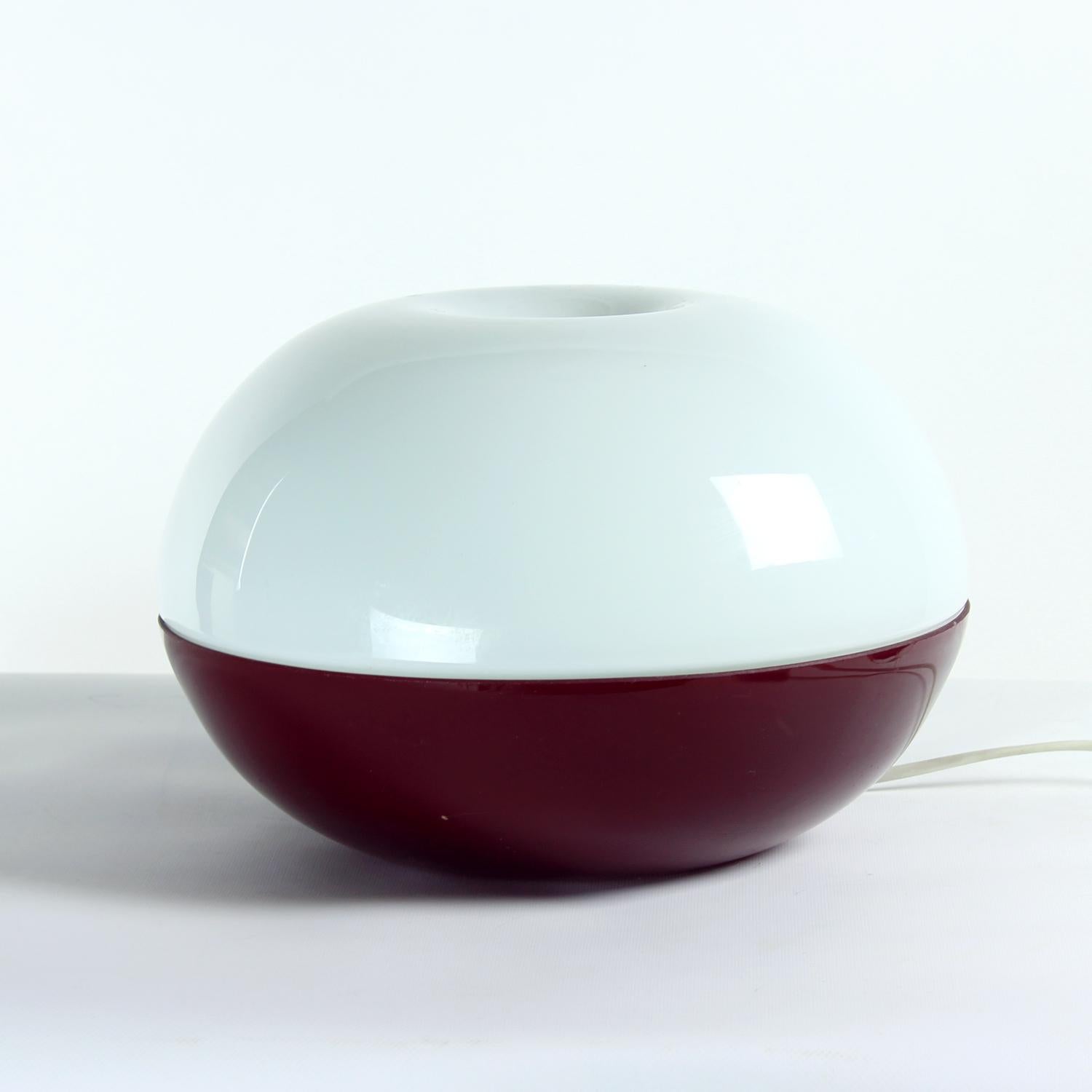 Preciosa lámpara de mesa vintage de forma y color interesantes. La lámpara se compone de dos partes, todas de cristal opalino. La parte inferior es de cristal burdeos oscuro (o morado oscuro), la superior es de cristal blanco. Funciona con una