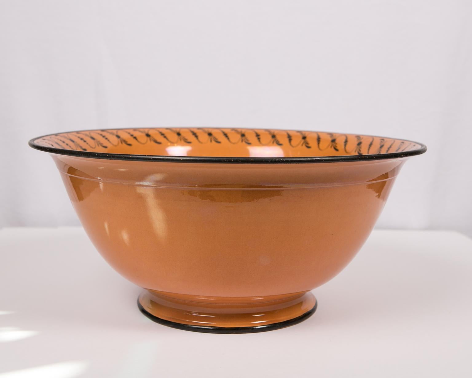 This large English punch bowl is painted in a soft orange with a simple black neoclassical trim on the inner border and edges along the top and bottom. 
Made circa 1840, the shape of the bowl is deep, with steep rounded sides rising from a short