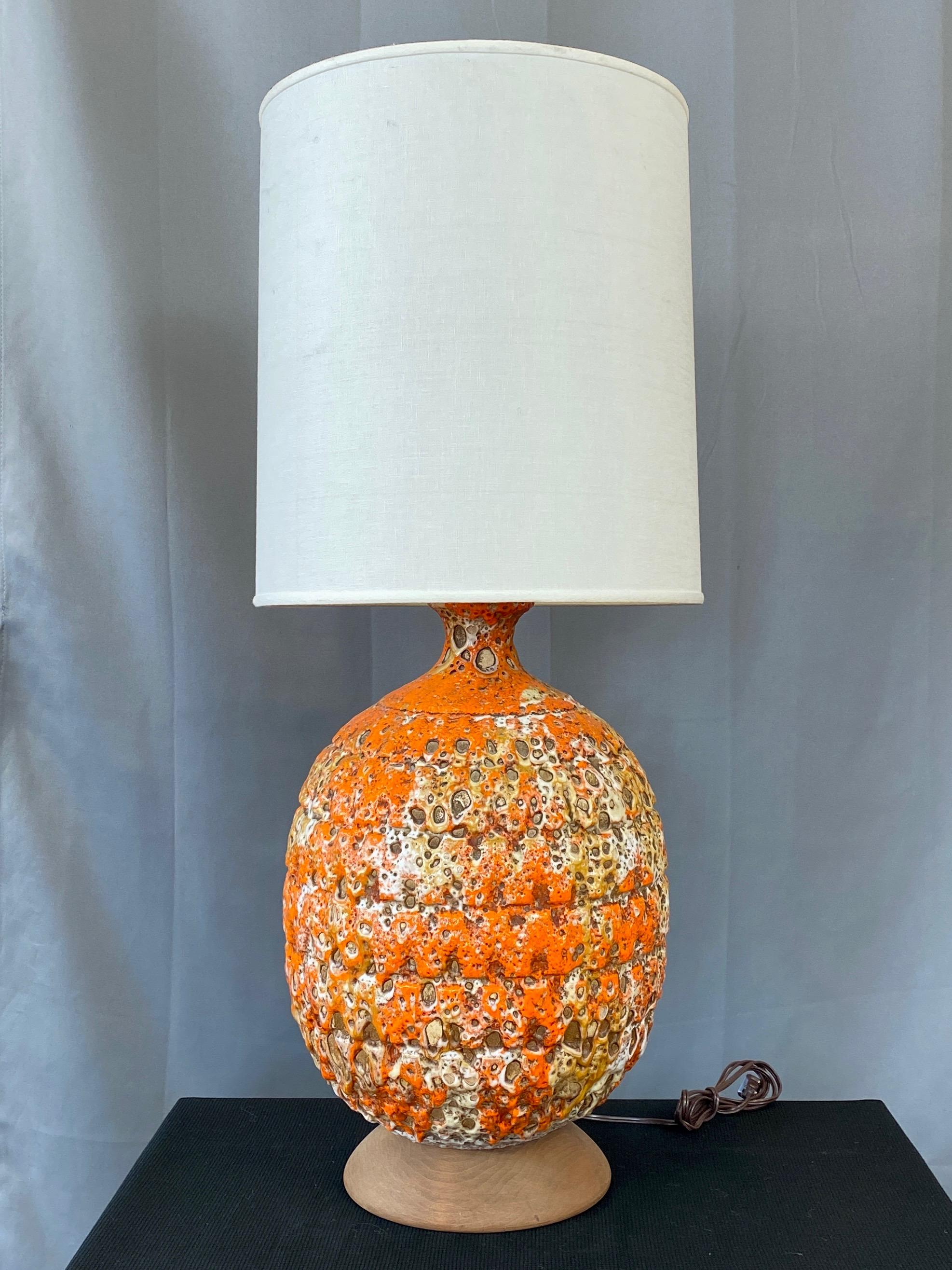 A large and impressive mid-century modern orange fat lava glazed ceramic table lamp with shade.

Very thickly applied and molten-like blaze orange glaze with tan and white accents truly lives up to the fat lava moniker. Indicative of the more