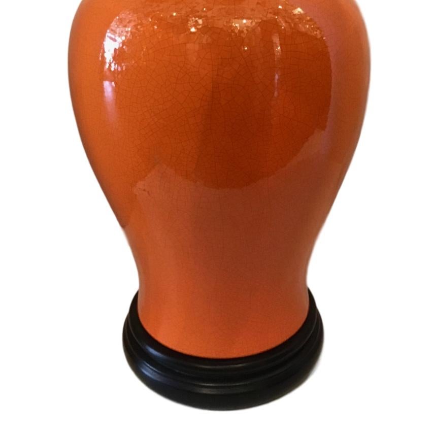 A large circa 1940s French ginger jar orange-glazed porcelain table lamp with crackled finish and wooden base.

Measurements:
Height of body 23