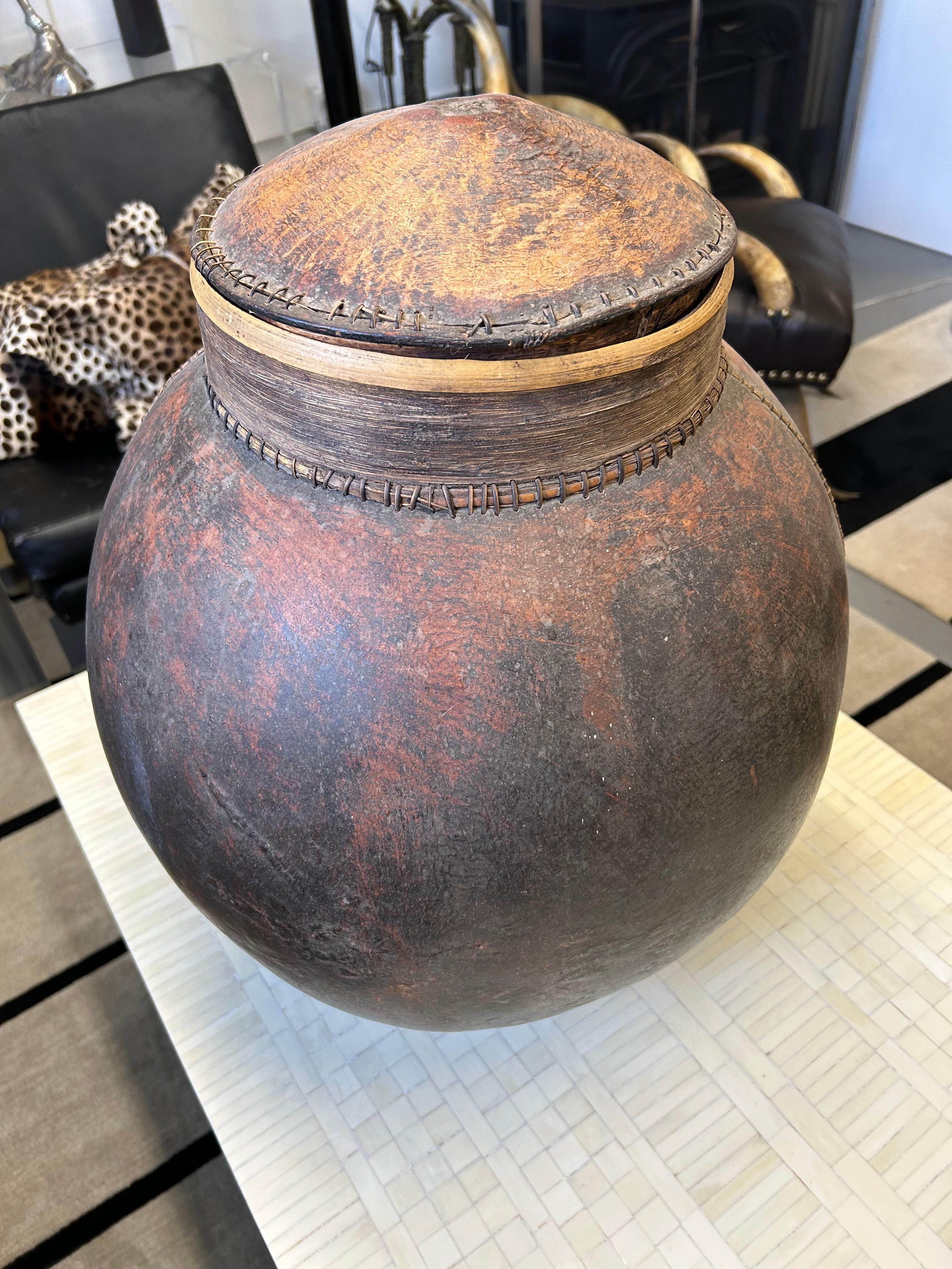 Impressionante in scala, grande vaso di zucca essiccata scavato a mano con coperchio e legno.  Cuciture visibili e favolosa patina marrone rossastra screziata.  L'apertura è di 9,75