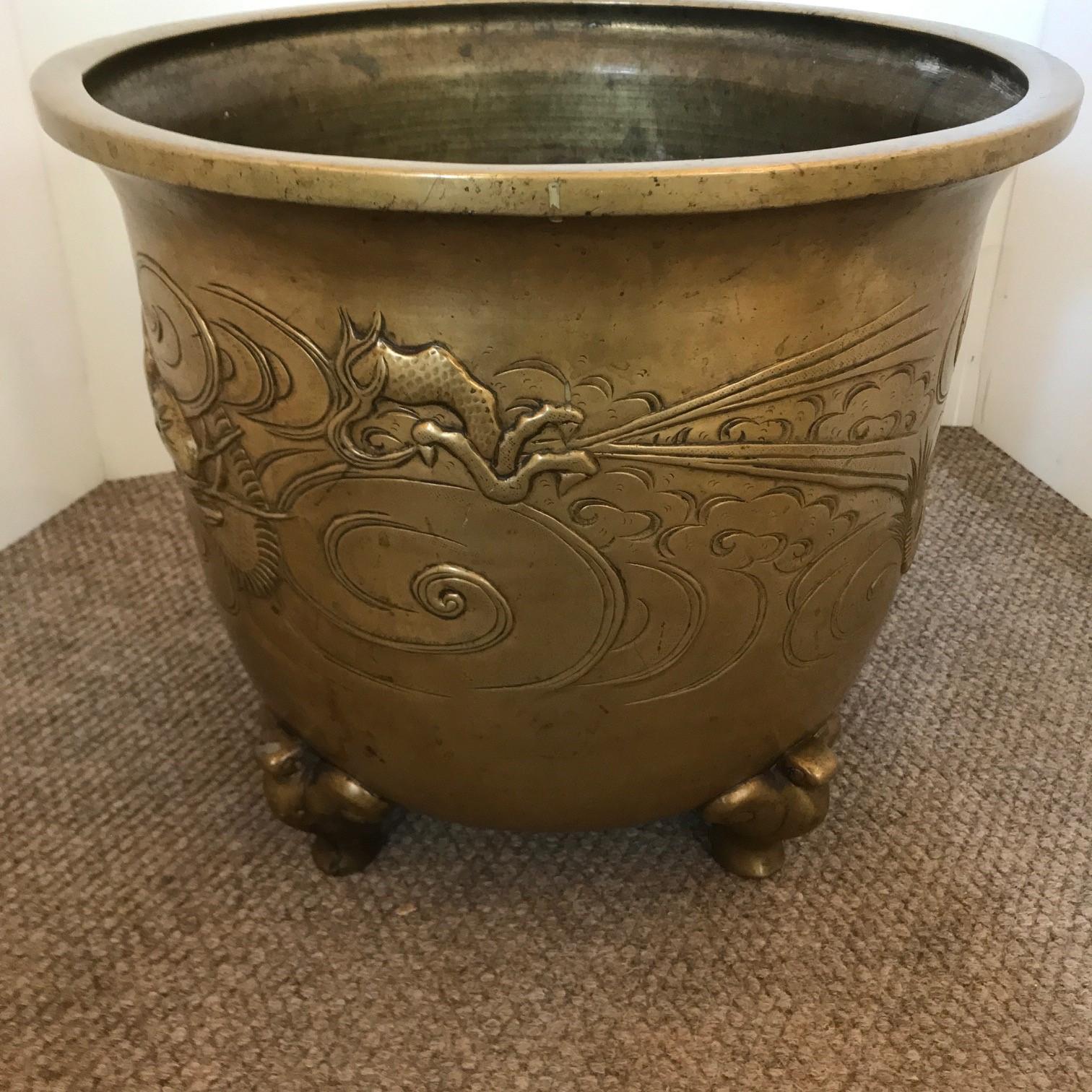 This handsome vessel is decorated with a bas-relief of dragons disputing a flaming pearl, the feet are modelled as a stylised bird (or possibly a stylised elephant)  The rim is inverted and flattened to aid in food preparation.

This vessel was a