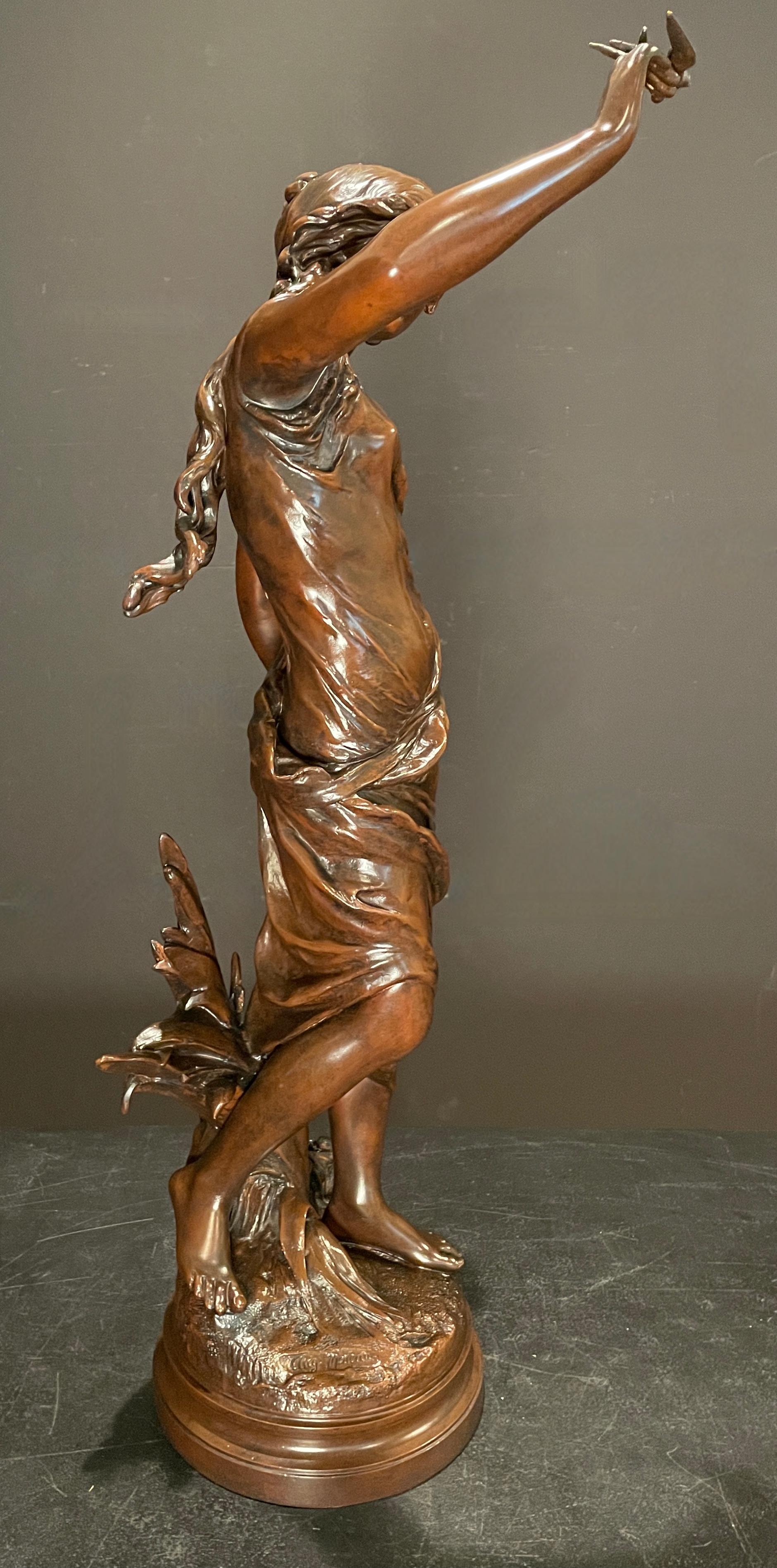 Grande sculpture française du XIXe siècle d'Auguste Moreau (1834-1917) représentant une jeune fille, sur sa main repose un petit oiseau d'amour. Fabriqué en spelter, ou métal en pot, avec une belle patine chaude et riche en brun chocolat. Signature