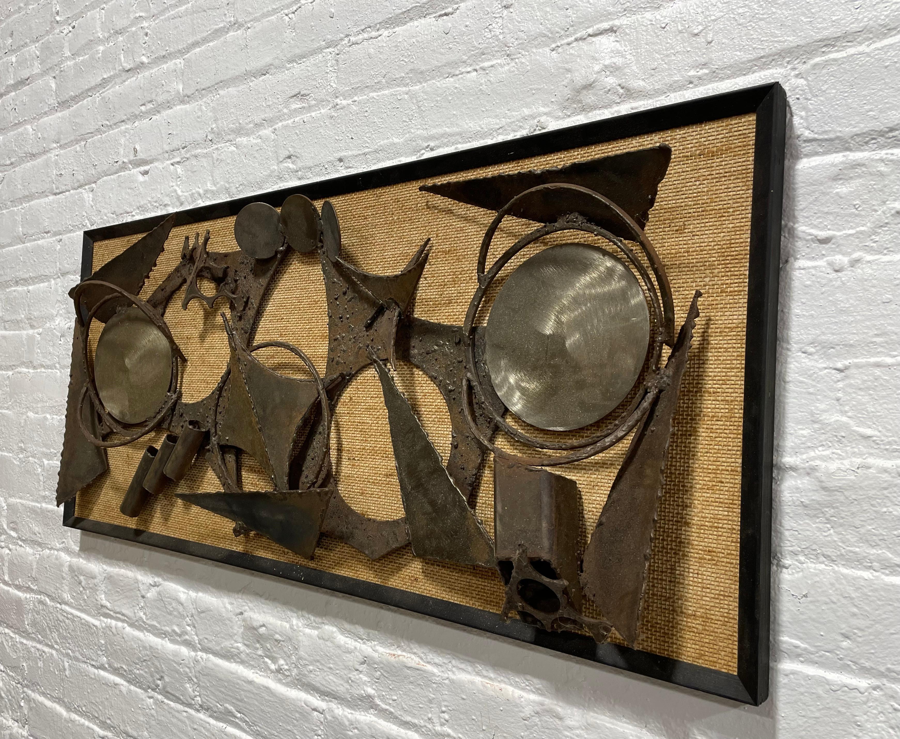 Large framed Mid Century Modern Brutalist Artwork.  Torch-cut and welded metal on grasscloth textile. Unsigned.  Incredible piece, heavy and well made. A few nicks and scuffs, as expected for a vintage piece. Ready to hang.