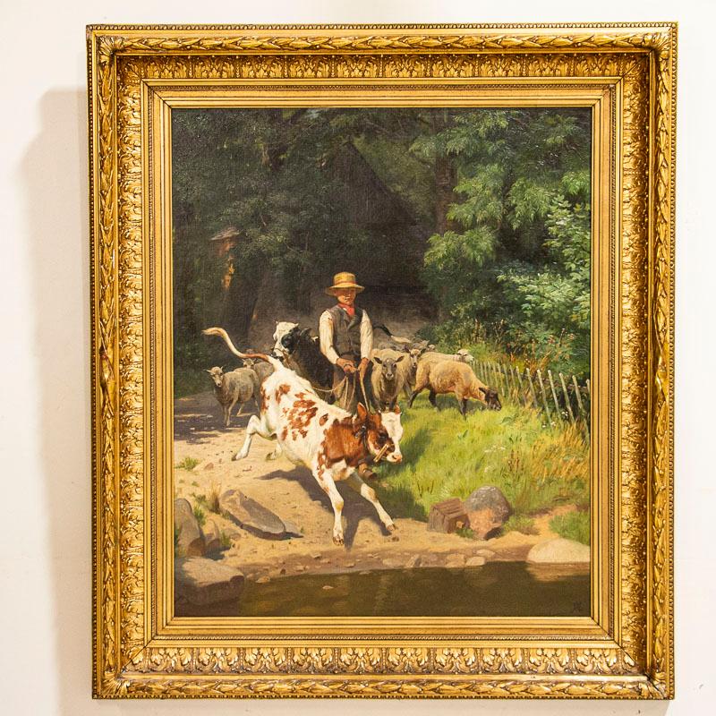 This large and wonderfully executed painting portrays the bucolic scene of a farm boy leading a calf to water with sheep behind. The painting is just under 5' tall measured at the outside of the heavily carved gold gilt frame. The signed monogram of