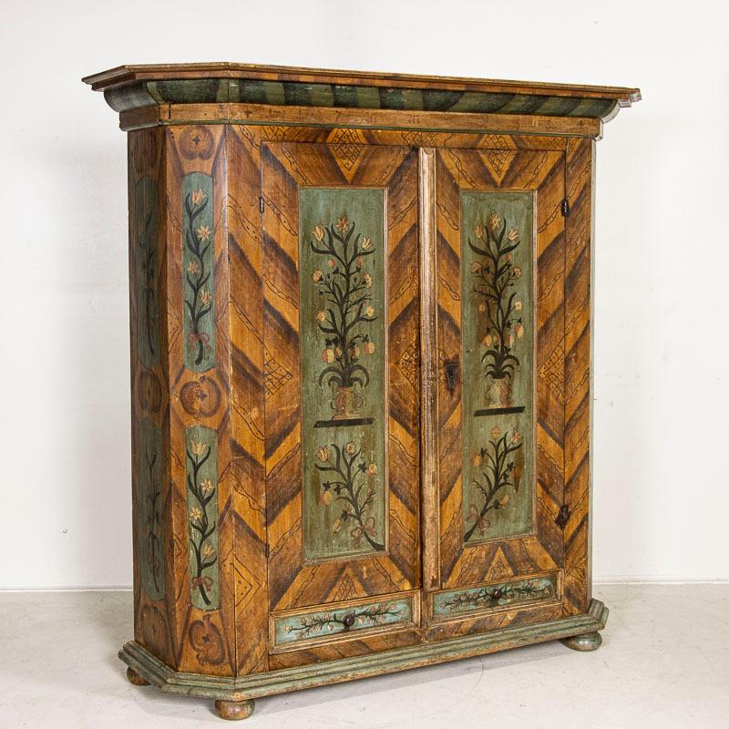 Occasionally we find a special, one of a kind piece that captures ones heart and imagination. Such is the case with this lovely original hand-painted armoire or shrunk from Germany. Beautiful floral and vine motif with soft colors of green, cream,