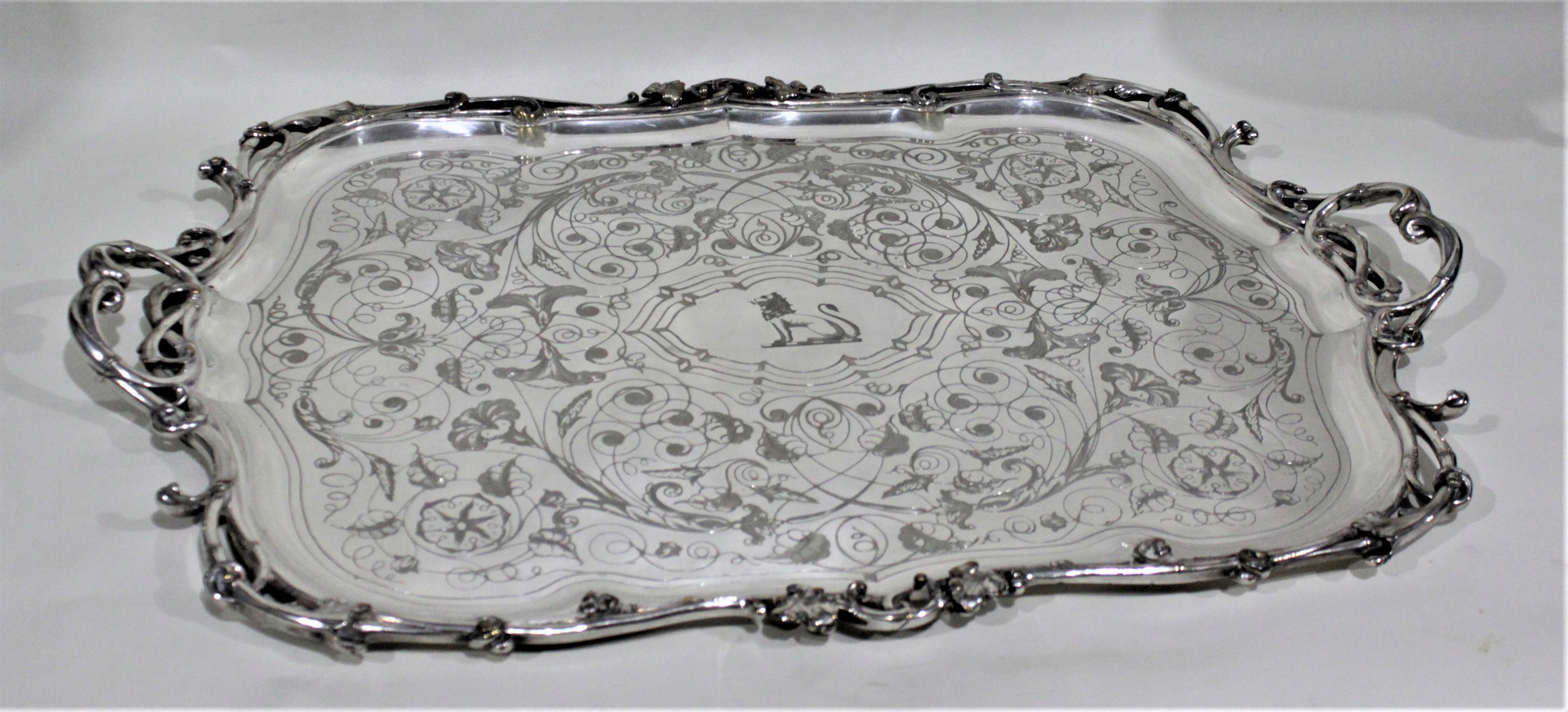 This very large and substantial antique silver plated serving tray was made in France around the turn of the century in the Edwardian style. The surface of the tray is very ornately engraved with vines and flowers with a seated lion in the central