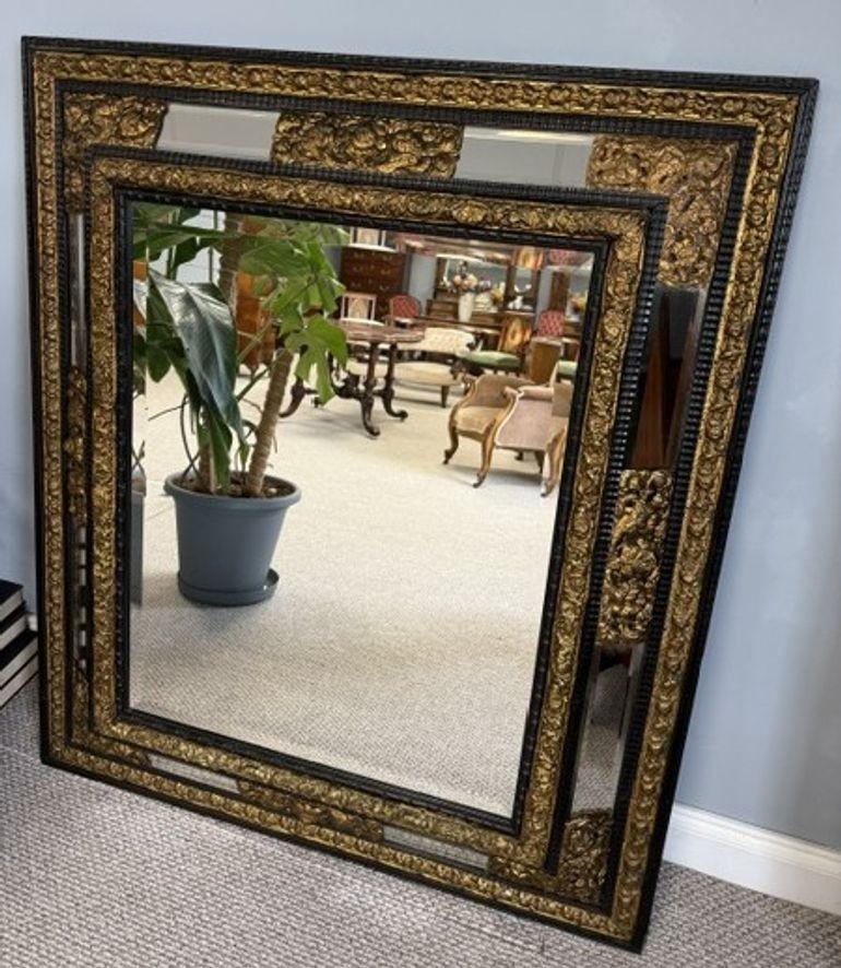 This large, ornate mirror features a stunning bevelled edge that adds depth and dimension to the reflective surface. The intricate, decorative wooden surround is crafted with care, showcasing a refined, vintage-inspired design that brings