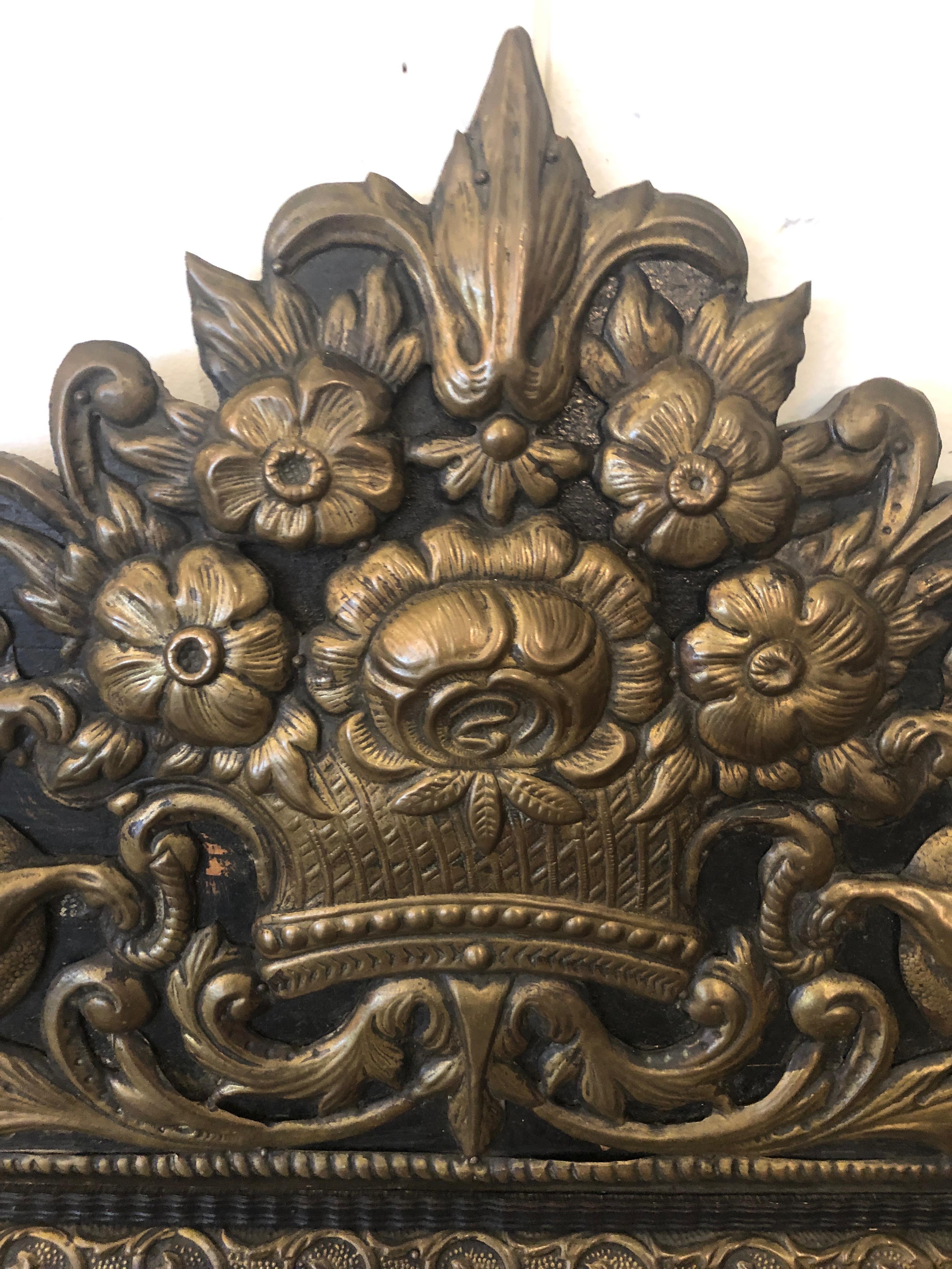 Elegant and large Napoleon III repousse mirror having an ornate, heavily embellished pediment and other brass decoration in the corners of a bevelled rectangular mirror with smaller mirrored 3 dimensional side sections. The central rectangular