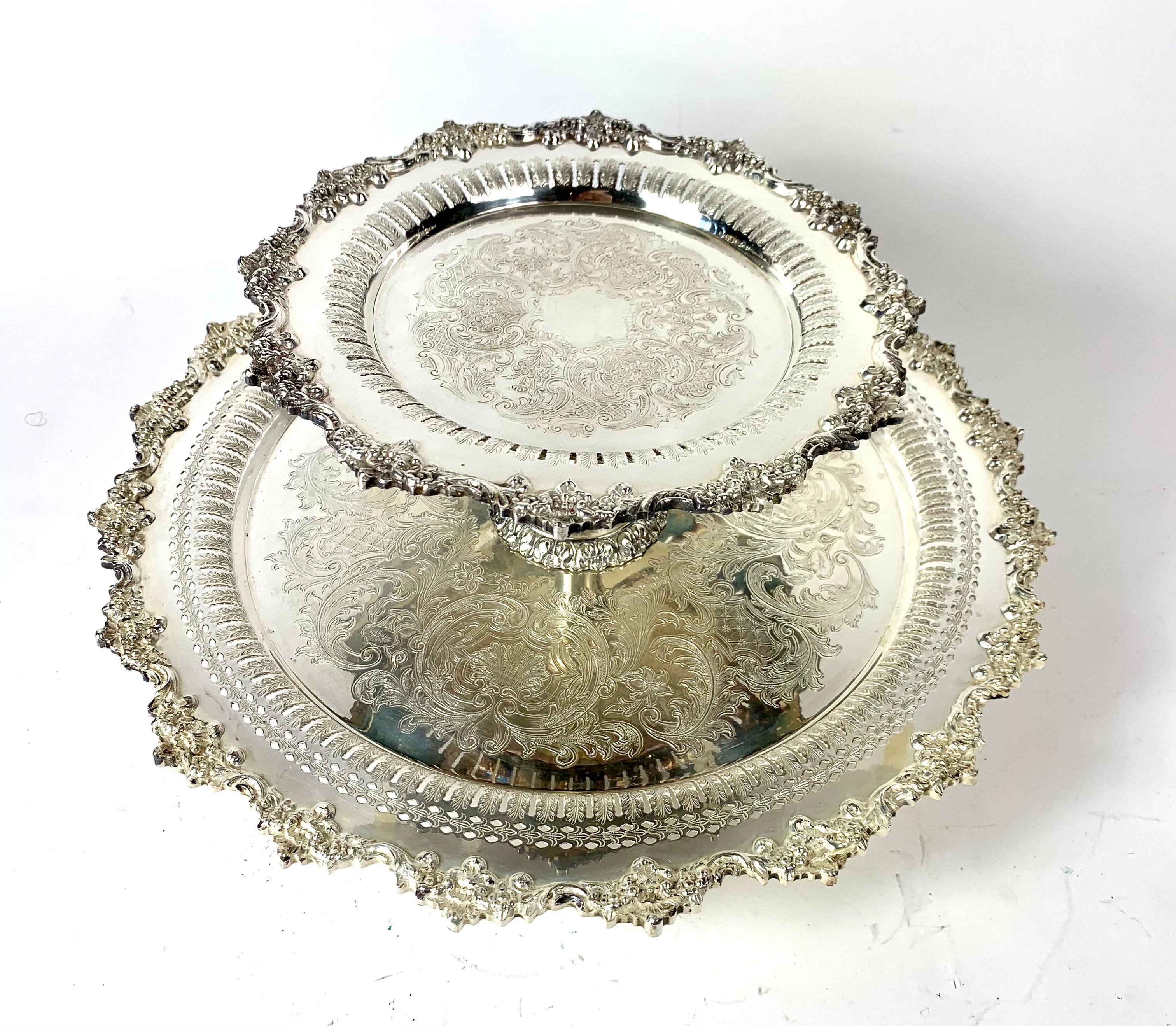 Large ornate silver plate two tier featuring an ornate foliated relief boarders, pierced interior rim and the center sections have a chased decoration. Underneath is the stepped pedestal base that the tiers revolve around. It is marked with crown