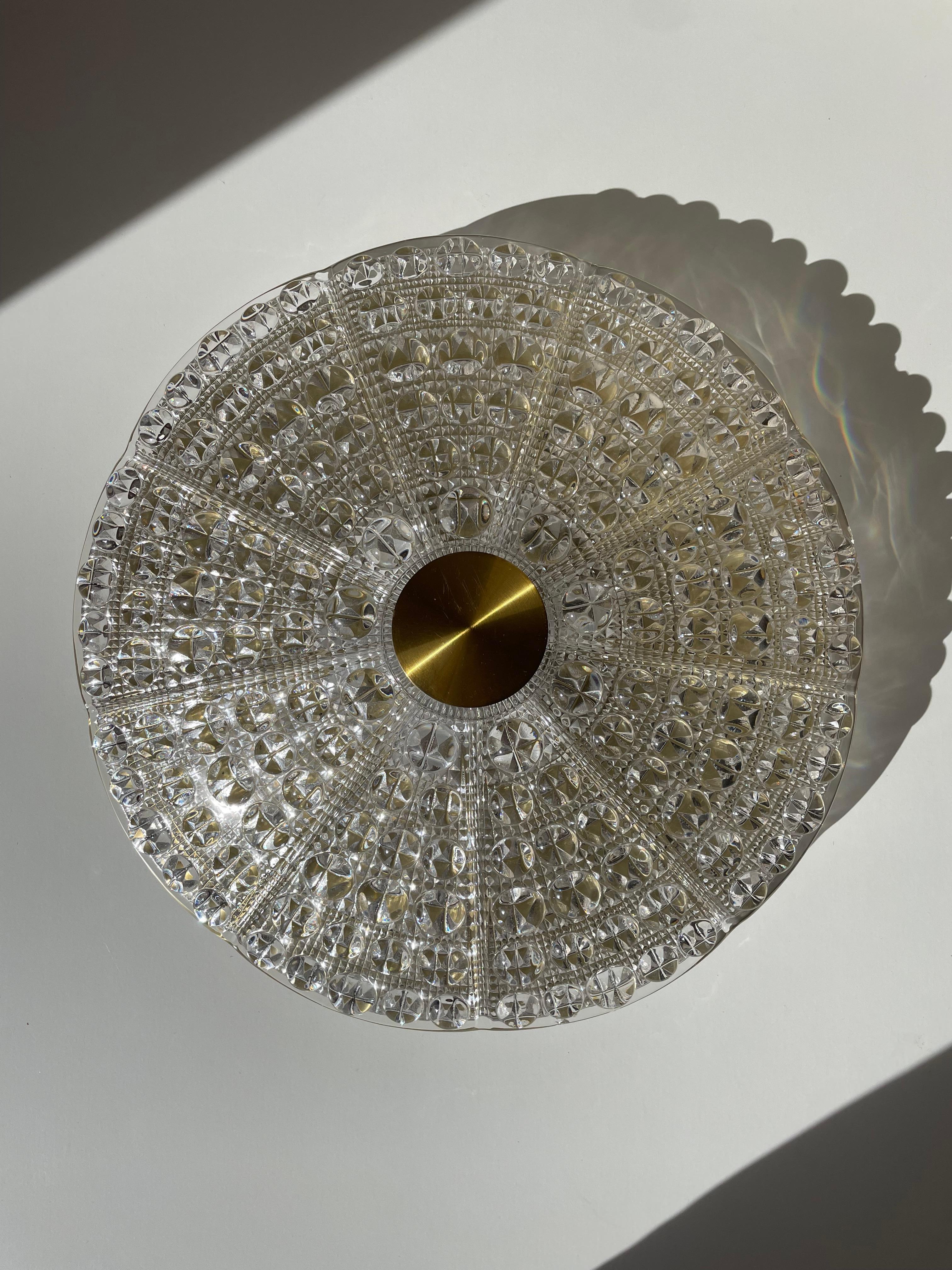 Solid crystal Swedish midcentury modern flush mount / wall sconce. Mounted on brass plate with brass details. Large and small round bubbles on the thick curved crystal dome with lined texture on the inside. Designed by Carl Fagerlund for Orrefors in