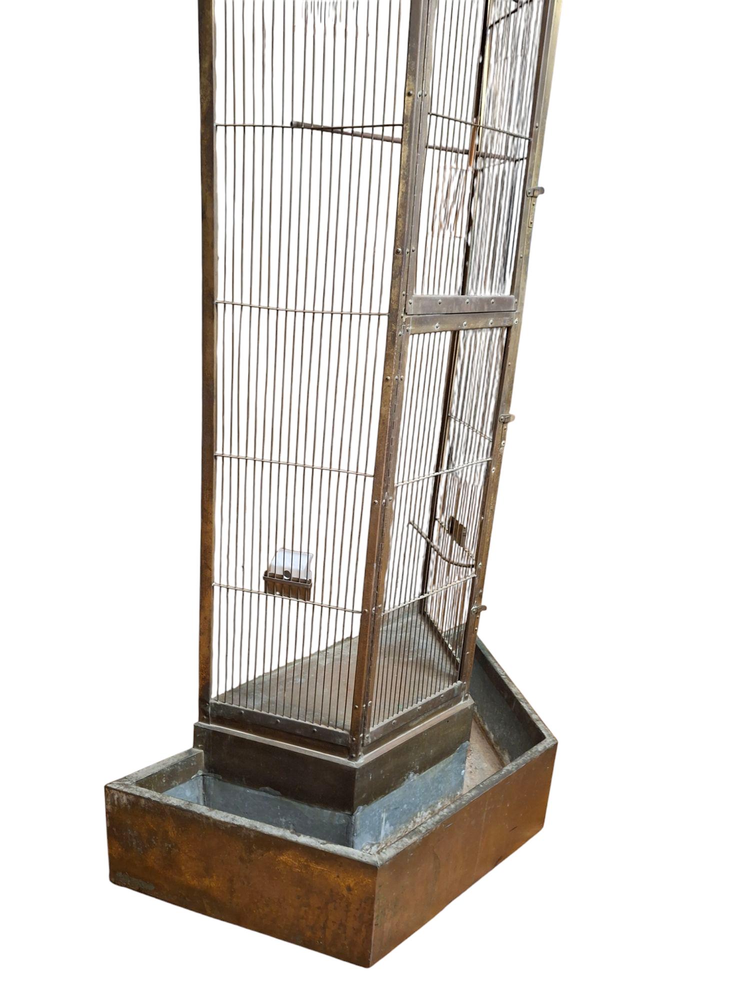 Large outdoor aviary/bird cage
Made with brass and steel in an unusual triangular shape with a pagoda style roof
2 perch rods, 2 mini wooden feeders, and 1 porcelain feeder inside