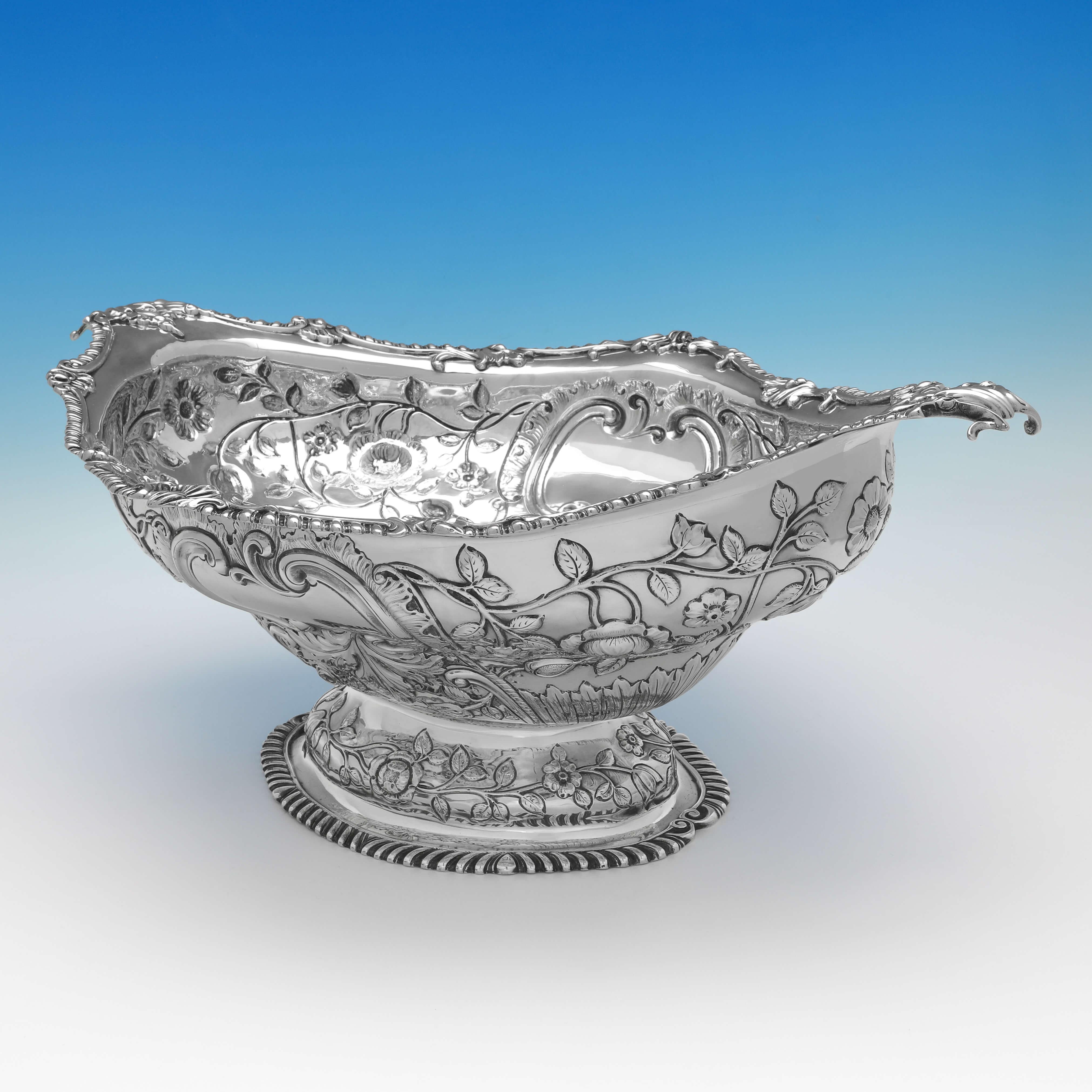 Hallmarked in London in 1908 by Charles Stuart Harris, this stunning and large, Edwardian, Antique Sterling Silver Centrepiece, is oval in shape, and features ornate chased decoration to the body and foot, and shaped gadroon borders. 

The dish