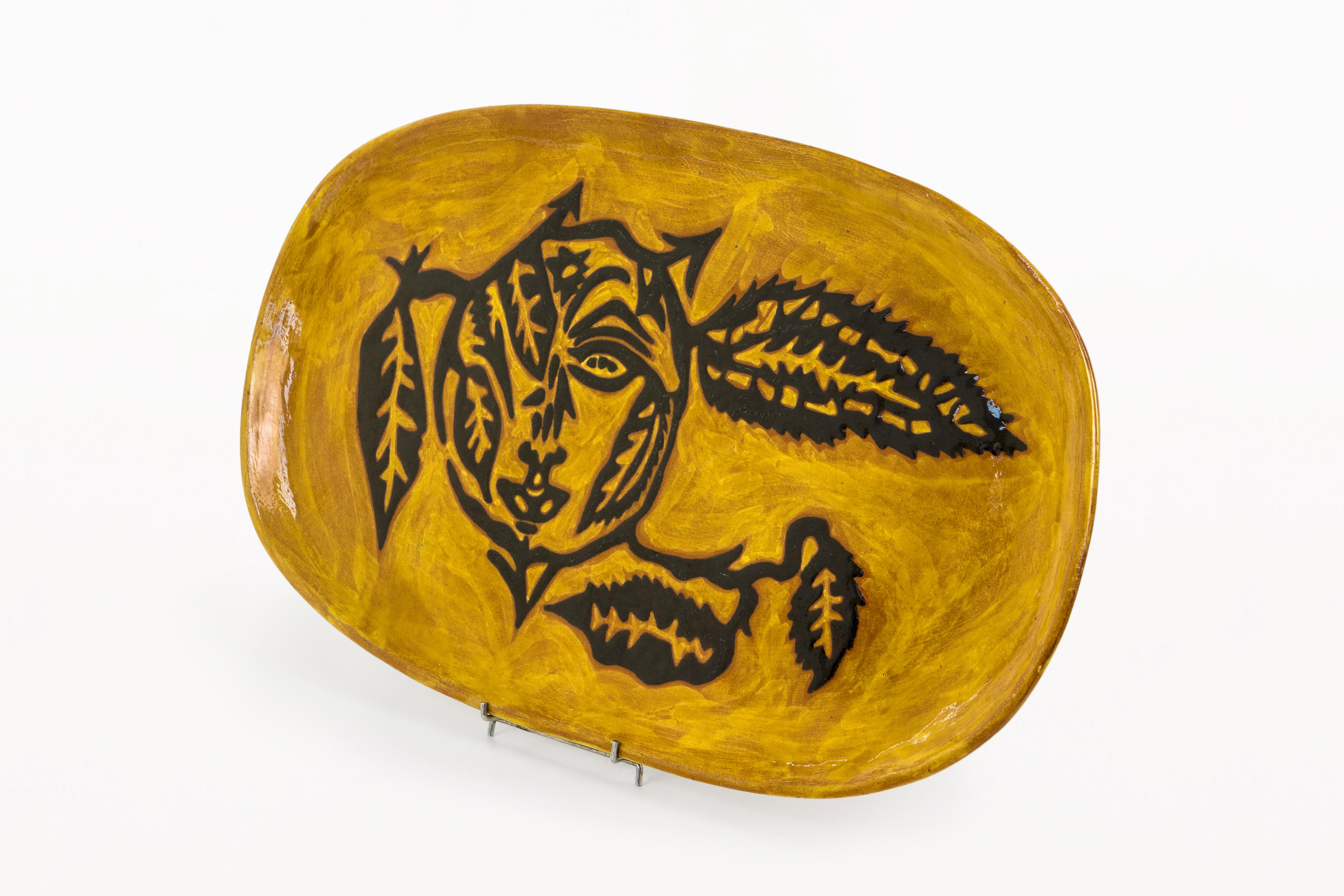 DESCRIPCIÓN: Gran Plato Ovalado de Cerámica para el Sol de Jean Lurçat, circa 1950, Francia.
Gran plato oval de cerámica, con decoración central de un sol estilizado y hojas. Fondo amarillo esmaltado con diseños negros y marrones. Firma esmaltada