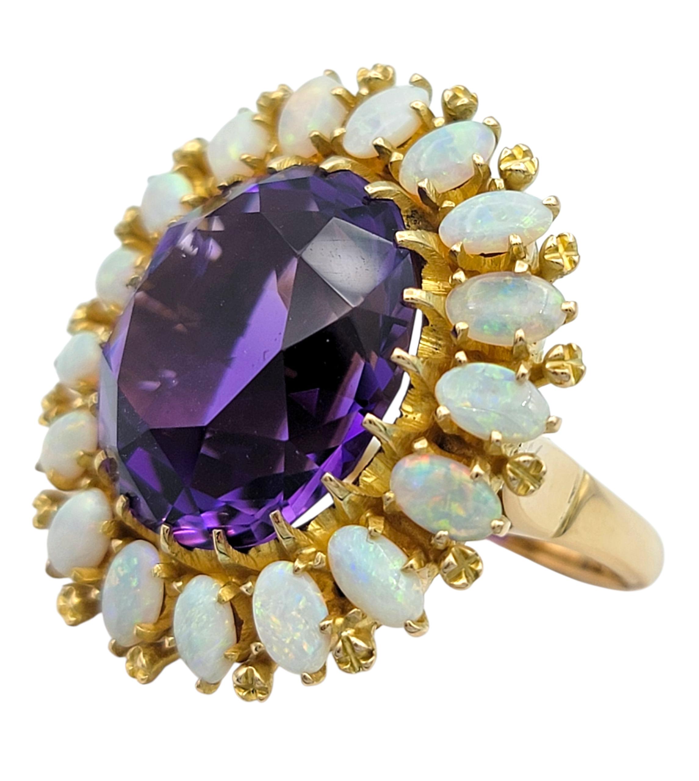 Radieuse et royale, cette remarquable bague capte le regard avec en son centre une améthyste ovale de 20,16 carats, entourée d'un halo lumineux d'opales irisées. La pierre précieuse d'un violet profond brille d'une richesse veloutée, tandis que les