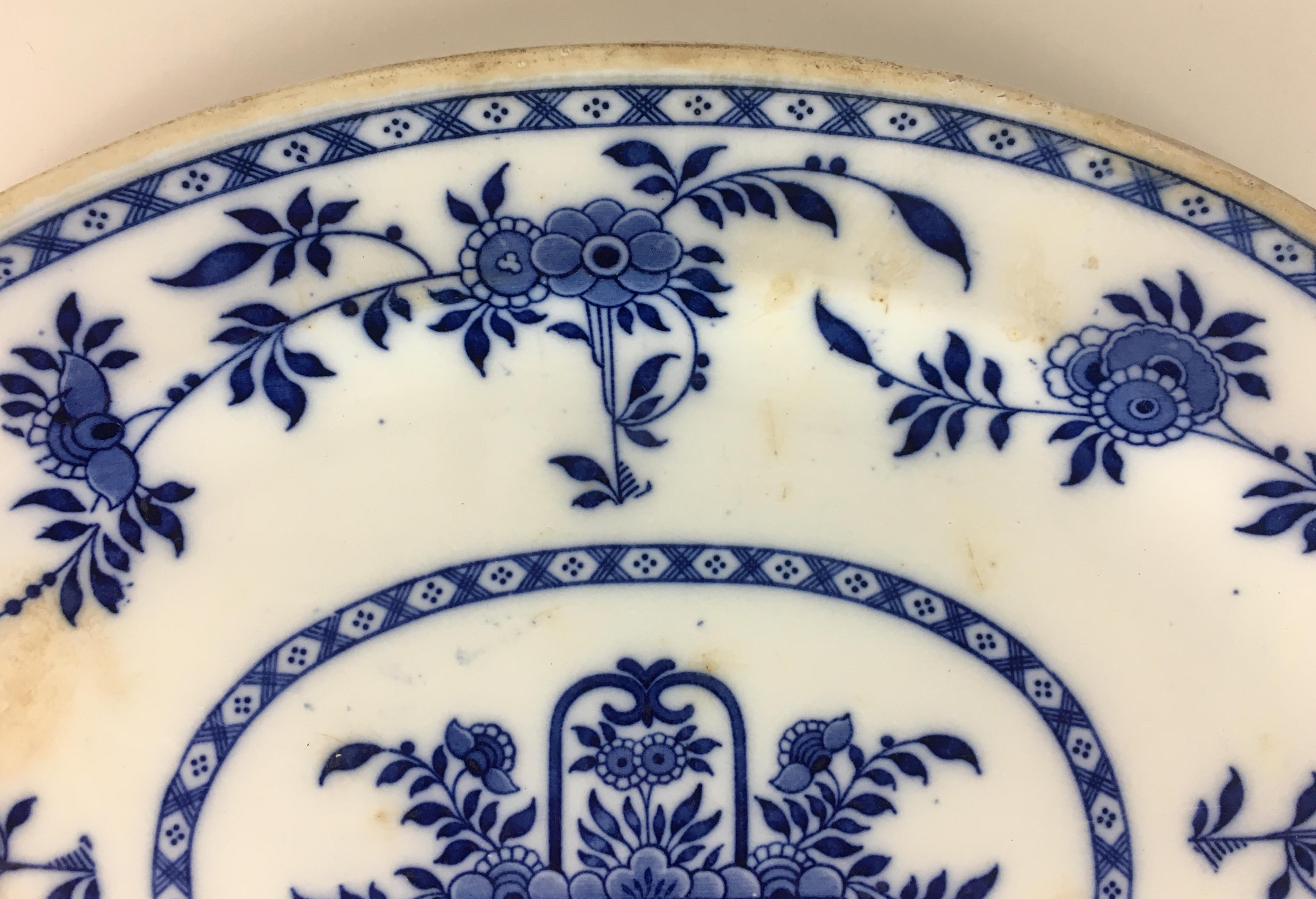 Delft earthenware dish with classical blue and white camaïeu floral design with large floral basket in the centre, circa 1920s. 
Maker's with other impressed marks on the bottom. 

On the edge, fine lace and blue threads. 
Period: Late 19th-early