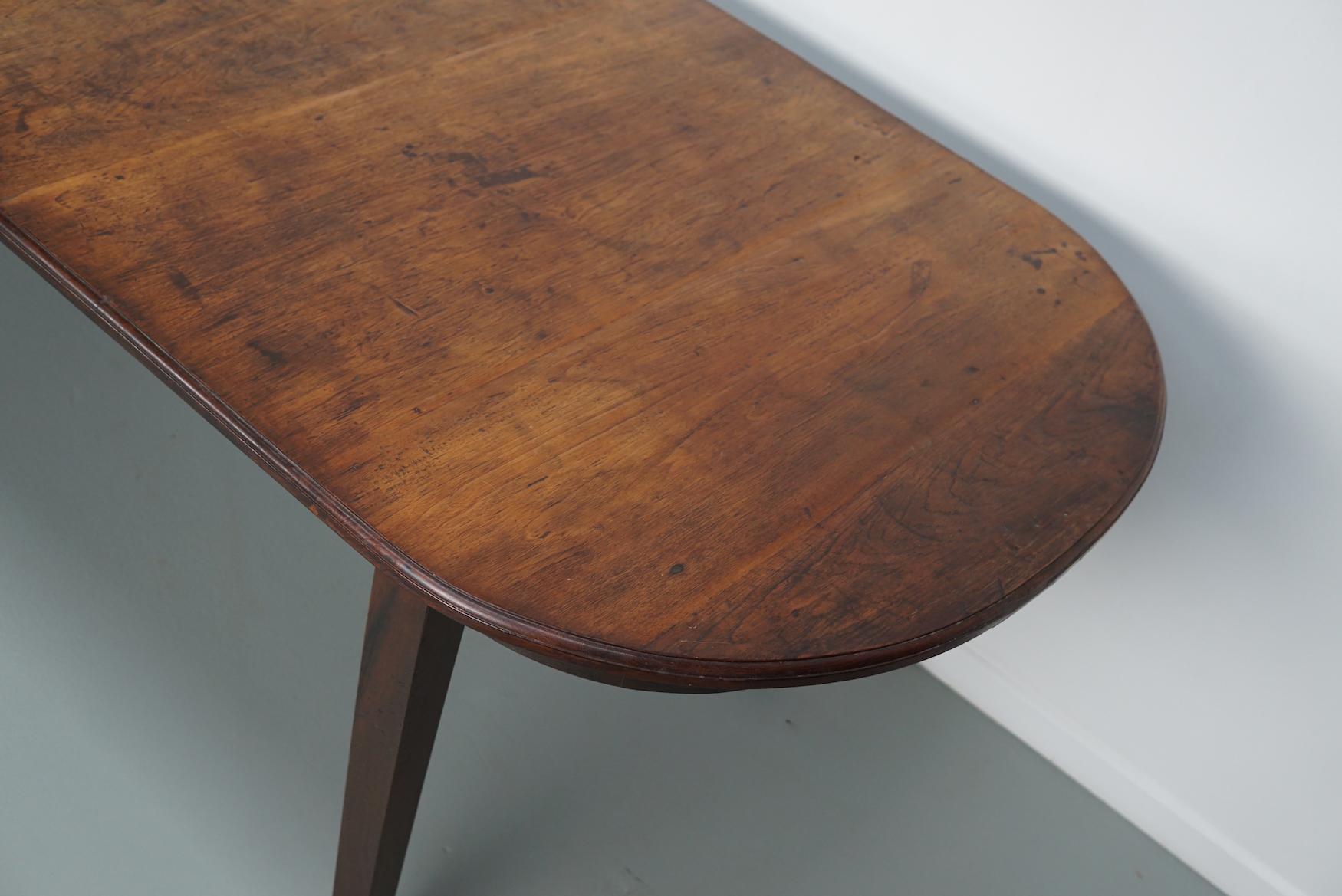 This elegant table was made in the Netherlands / Indonesia in the mid 20th century. It has a tabletop made from large pieces of antique school tables. The table was made in solid Indonesian teak with a beautiful grain pattern. It has a warm color