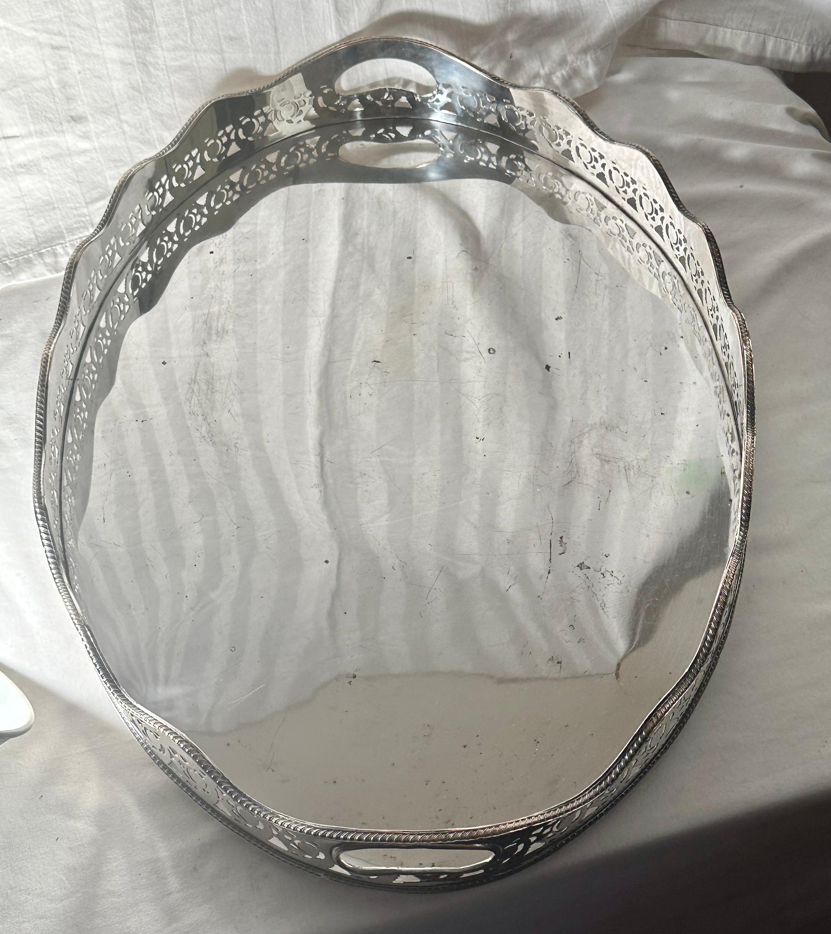Large Oval Edwardian Gallery Butler Tray Hallmarked Silver Plate.

Large oval Edwardian butler, serving tray features a broad pierced gallery with scalloped edges and inset handles.  It sits on 4 knob feet.  English Silver plate on copper Hallmark