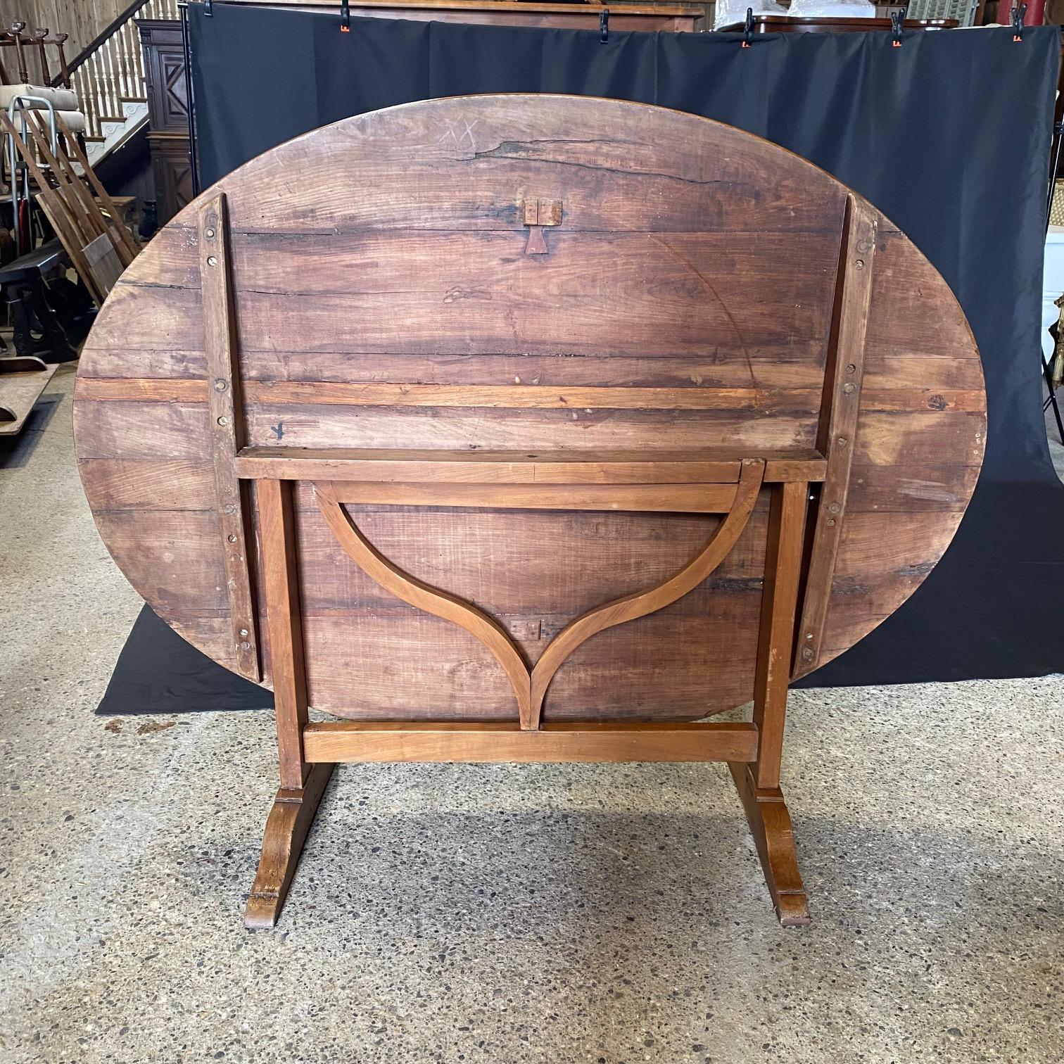 Lovely and large French early walnut tilt-top 'table de vendange,' or wine tasting table, circa late 1800s. Generous oval top circled by bentwood edge upon trestle base with triangular harp mechanism. Carved rounded feet and all hand-carved.