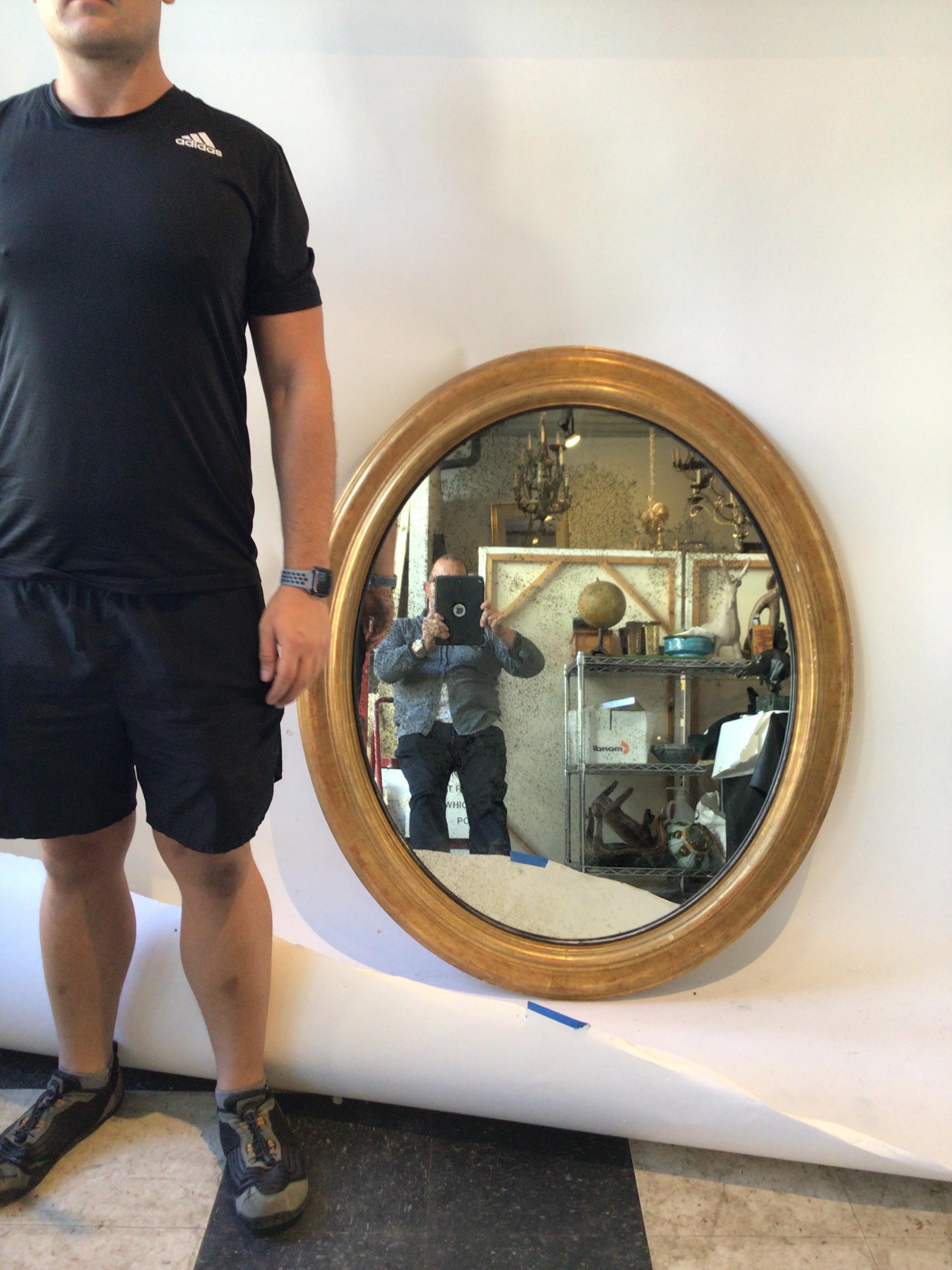 Large oval gilt wood framed mirror with aged mirror.