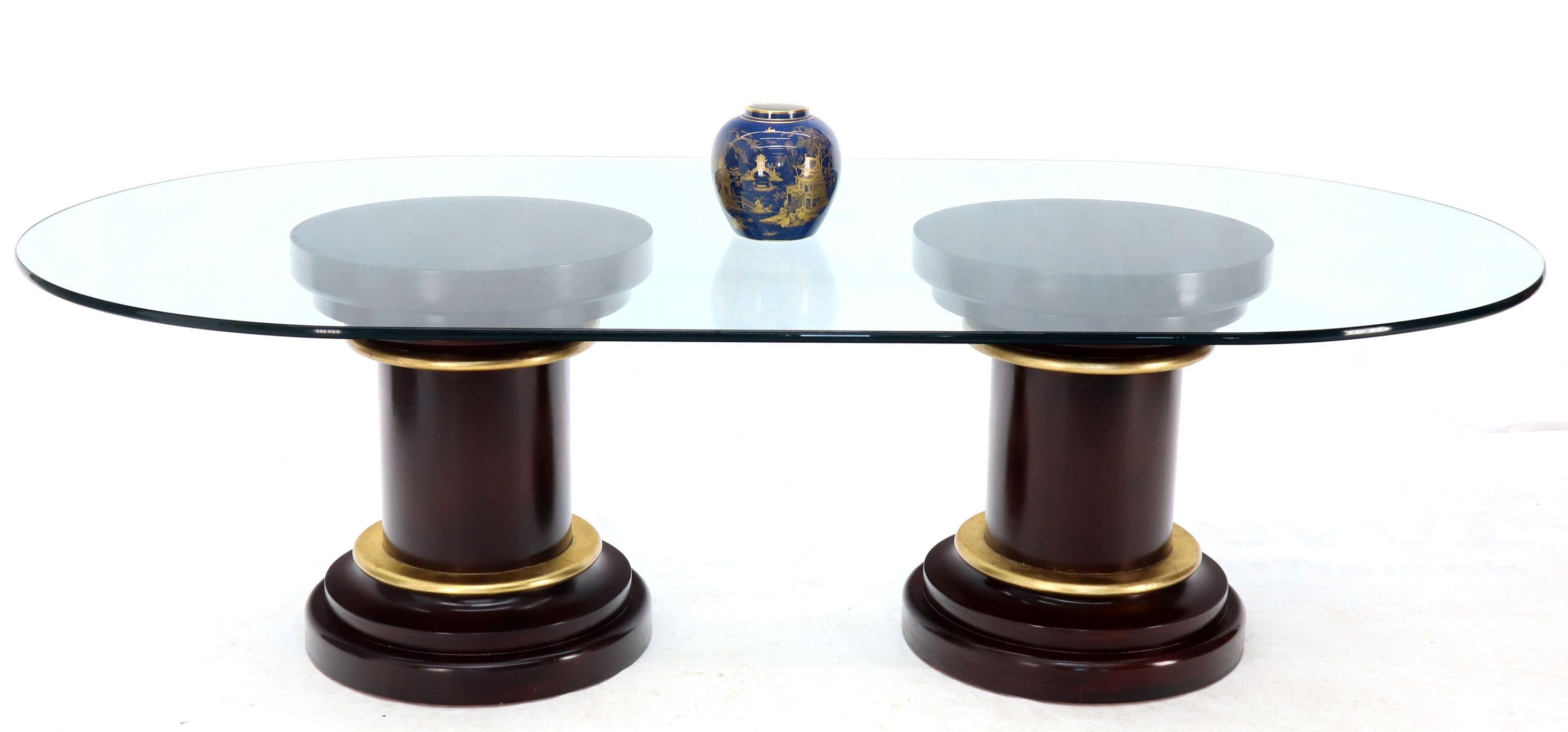Mid-Century Modern oversized oval glass top dining conference table. Mahogany pedestals bases with gold gilt decorative bezel or trim.