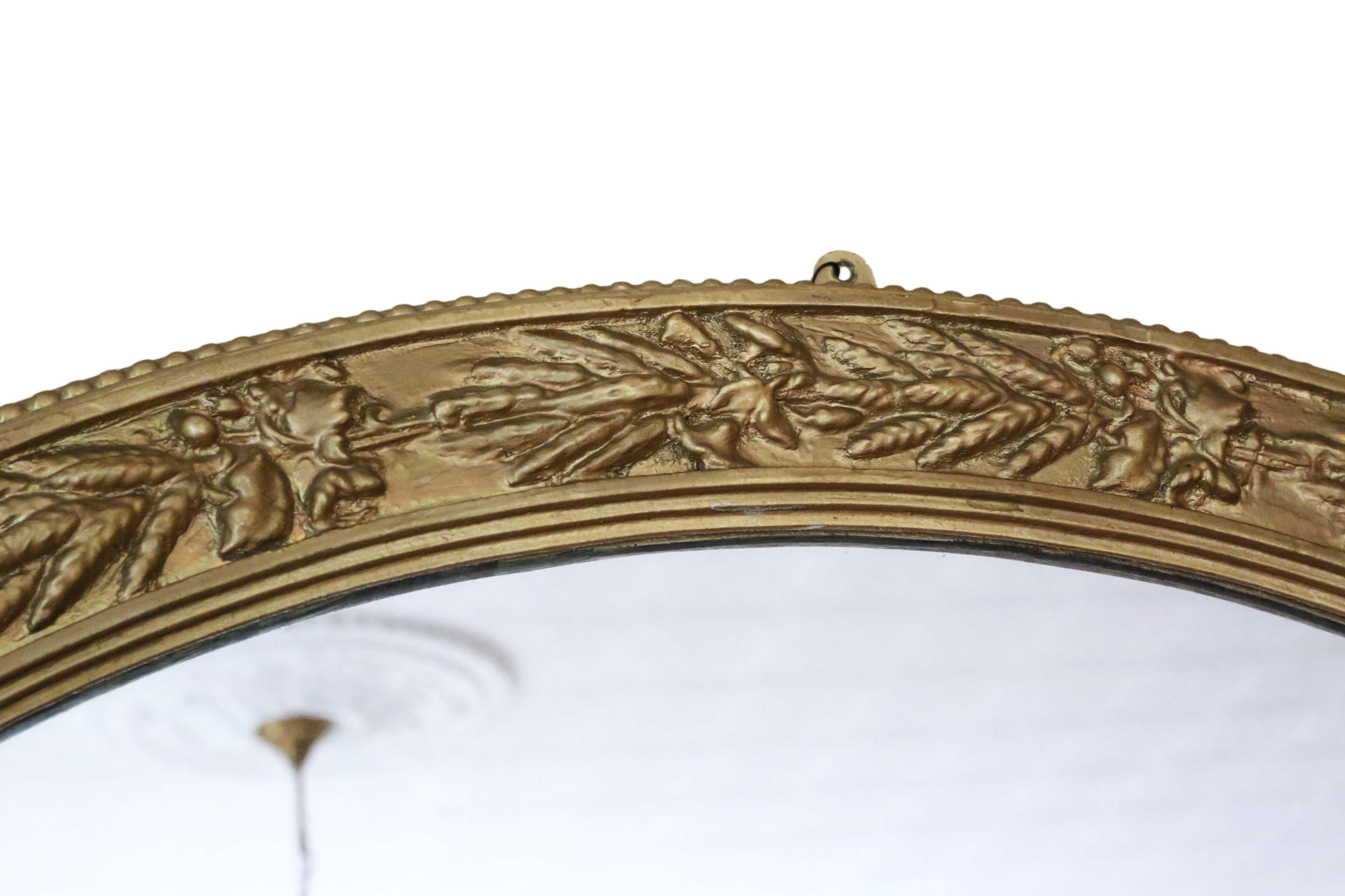 Antique large oval mid-19th century gilt overmantle wall mirror.
A charming mirror, that is full of age and character. The frame has some losses, which have been historically repainted then touched up over the years. No woodworm.
The mirrored