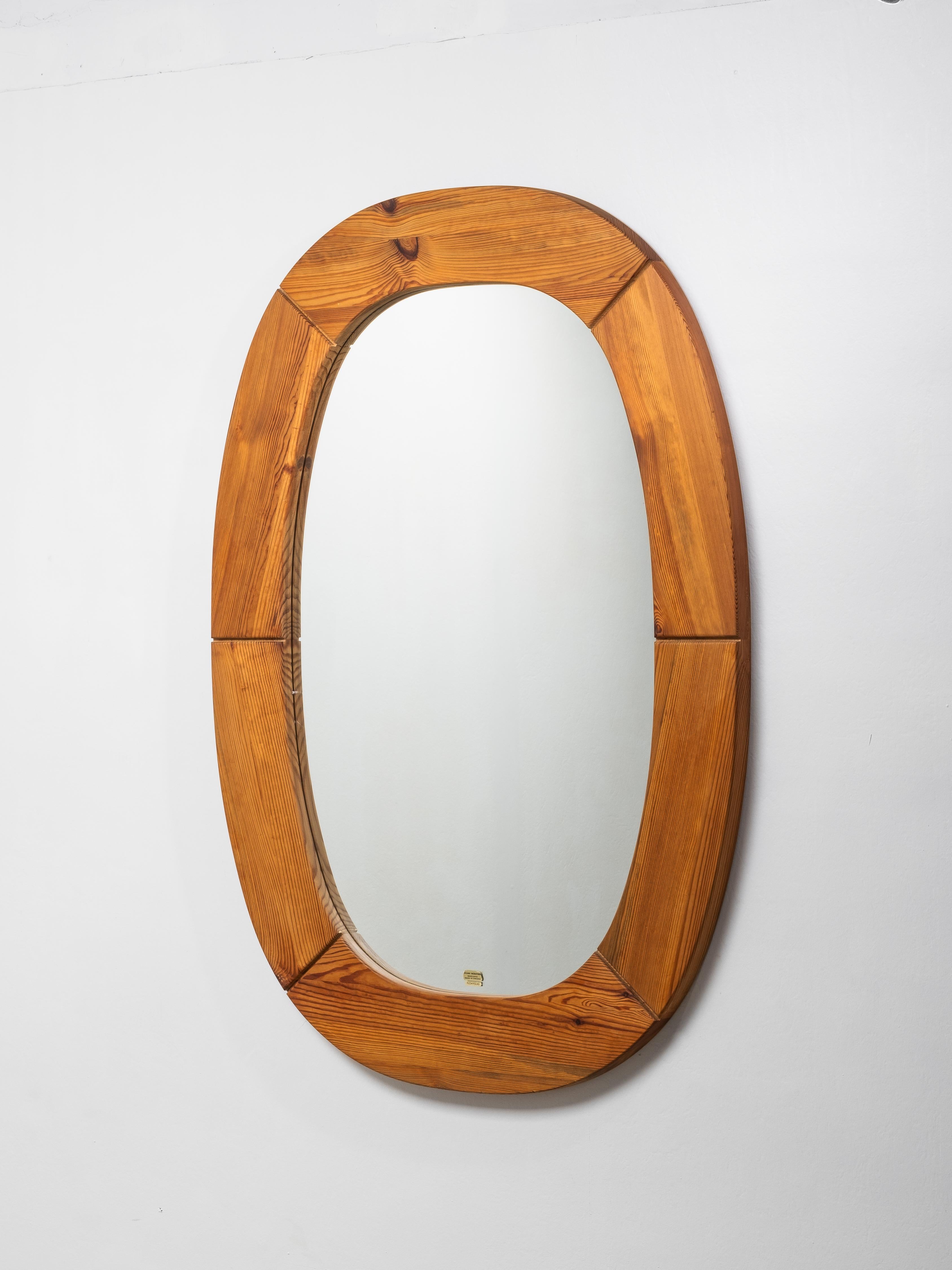 Miroir mural ovale de Glas Mäster, Markaryd, Suède, fabriqué dans les années 1970. Le cadre en pin massif présente une construction segmentée sculpturale avec un grain magnifiquement visible et une finition chaude aux tons de miel, caractéristique
