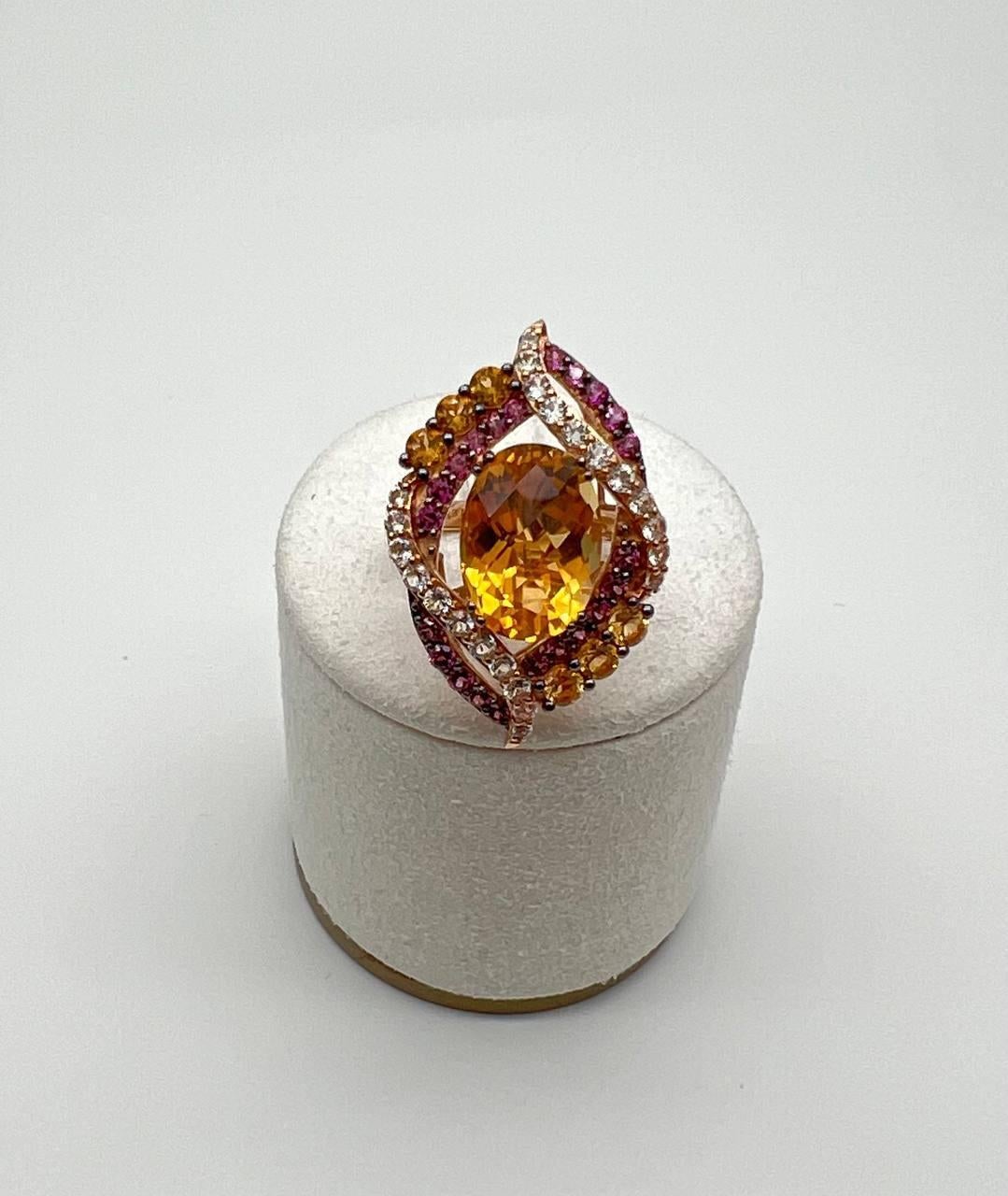 A symphony of color and elegance.

This striking statement ring features a radiant, oval-cut orange citrine gemstone at its heart. Encircling the center stone are intricate swirls of vibrant purple amethysts and orange citrines, interspersed with