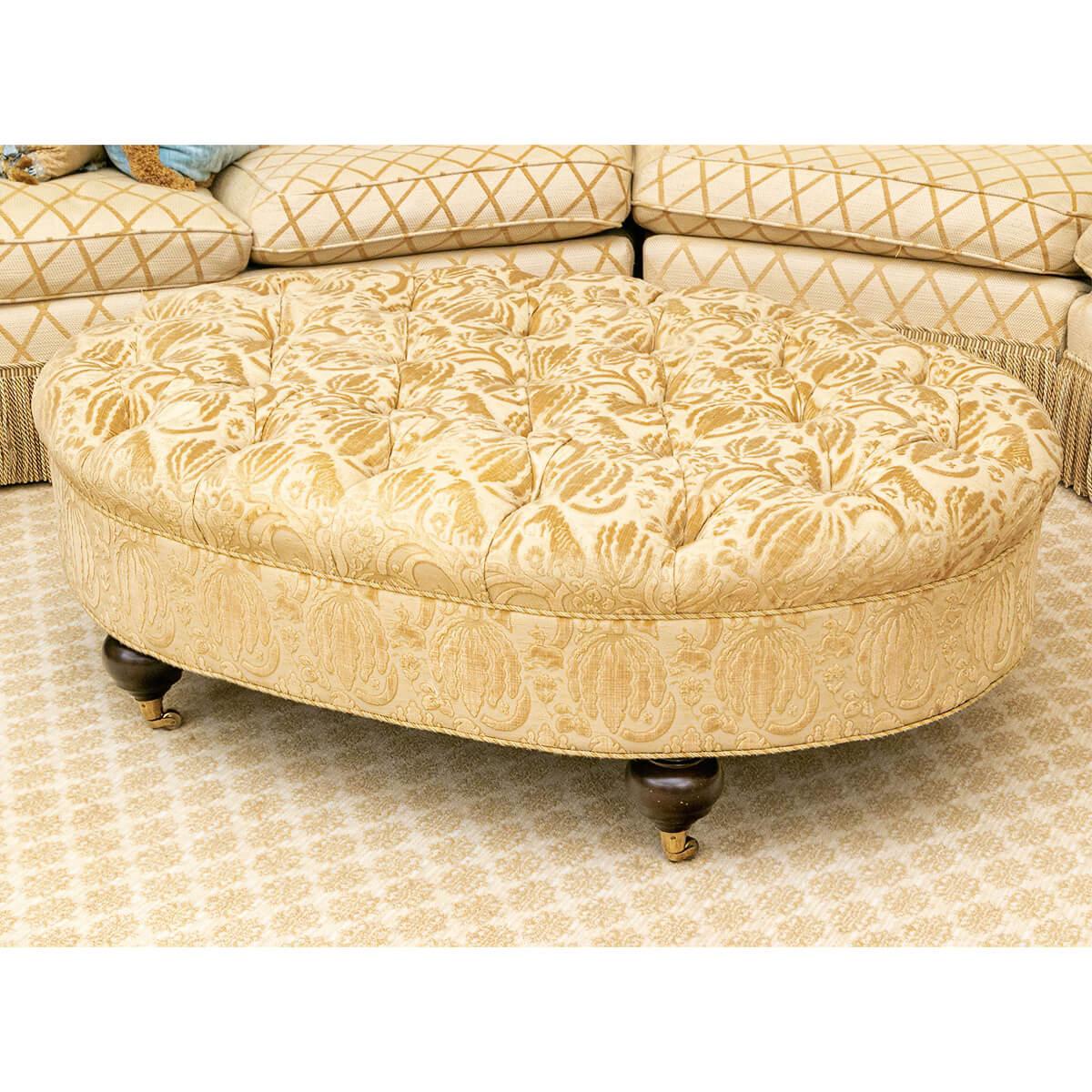 A classic form oval button tufted ottoman beautifully upholstered in a high-quality damask fabric with lovely contrasting luster. The piece is further trimmed in a coordinating gimp. The whole rests on four dark stained wood ball form feet with