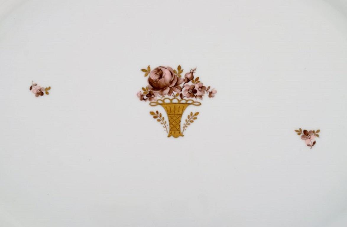 Grande piatto da portata ovale Royal Copenhagen Golden Basket in porcellana con decorazione a fiori e oro. Numero di modello 595/9011. 
Inizio del XX secolo.
Misure: 47,5 x 35 cm.
In ottime condizioni.
Timbrato.
Prima qualità di fabbrica.