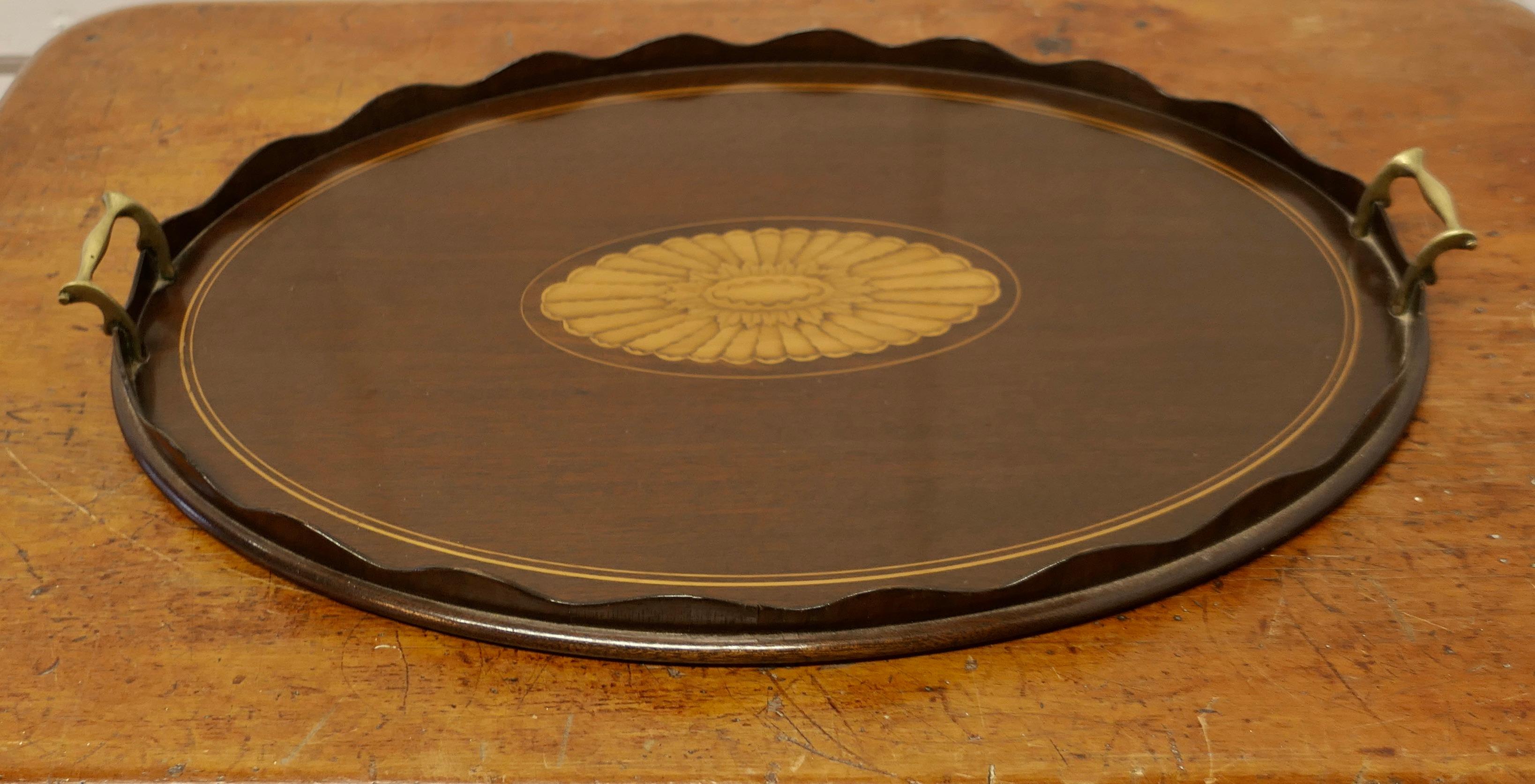 Large Oval Sheraton Style Tray.

This is a superb quality piece 
The tray is oval and decorated in the Sheraton style with a stylised floral inlay at the centre it has a raised scalloped edge and brass handles
This stylish tray has a good colour and