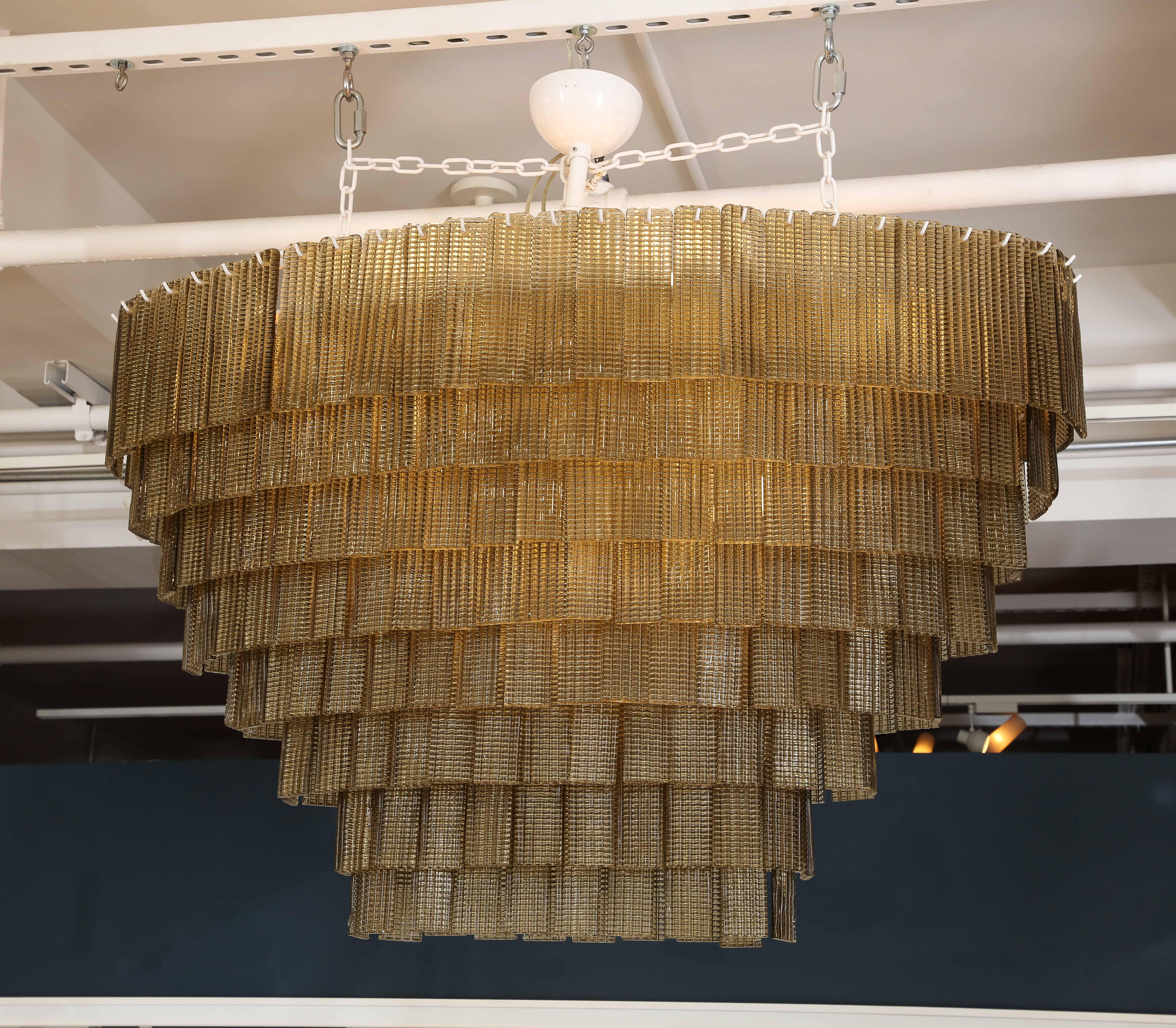 A large and elegant oval hand blown Murano chandelier consisting of eight tiers of more than one hundred rectangular, vertical, textured, ribbed pieces of glass in a single color best described as taupe, grayish bronze, suspended by one white canopy
