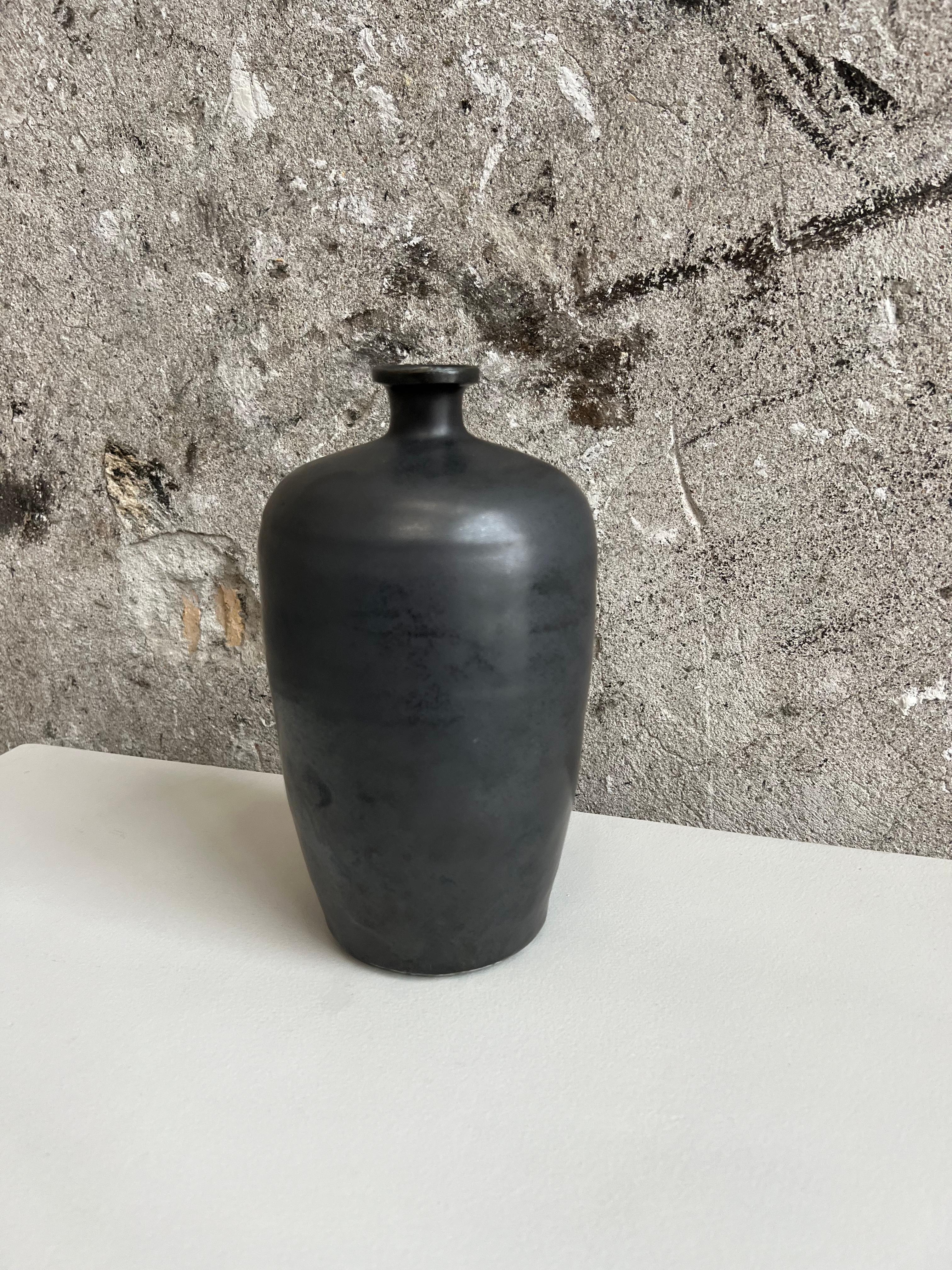 Schöne, glatte, glasierte Steingutvase in schwarzer Farbe. Diese Vase ist von traditionellen Gefäßen aus alten Filmen inspiriert und vermittelt ein antikes Gefühl mit einem modernen und minimalistischen Look.  Kann sowohl funktional als auch
