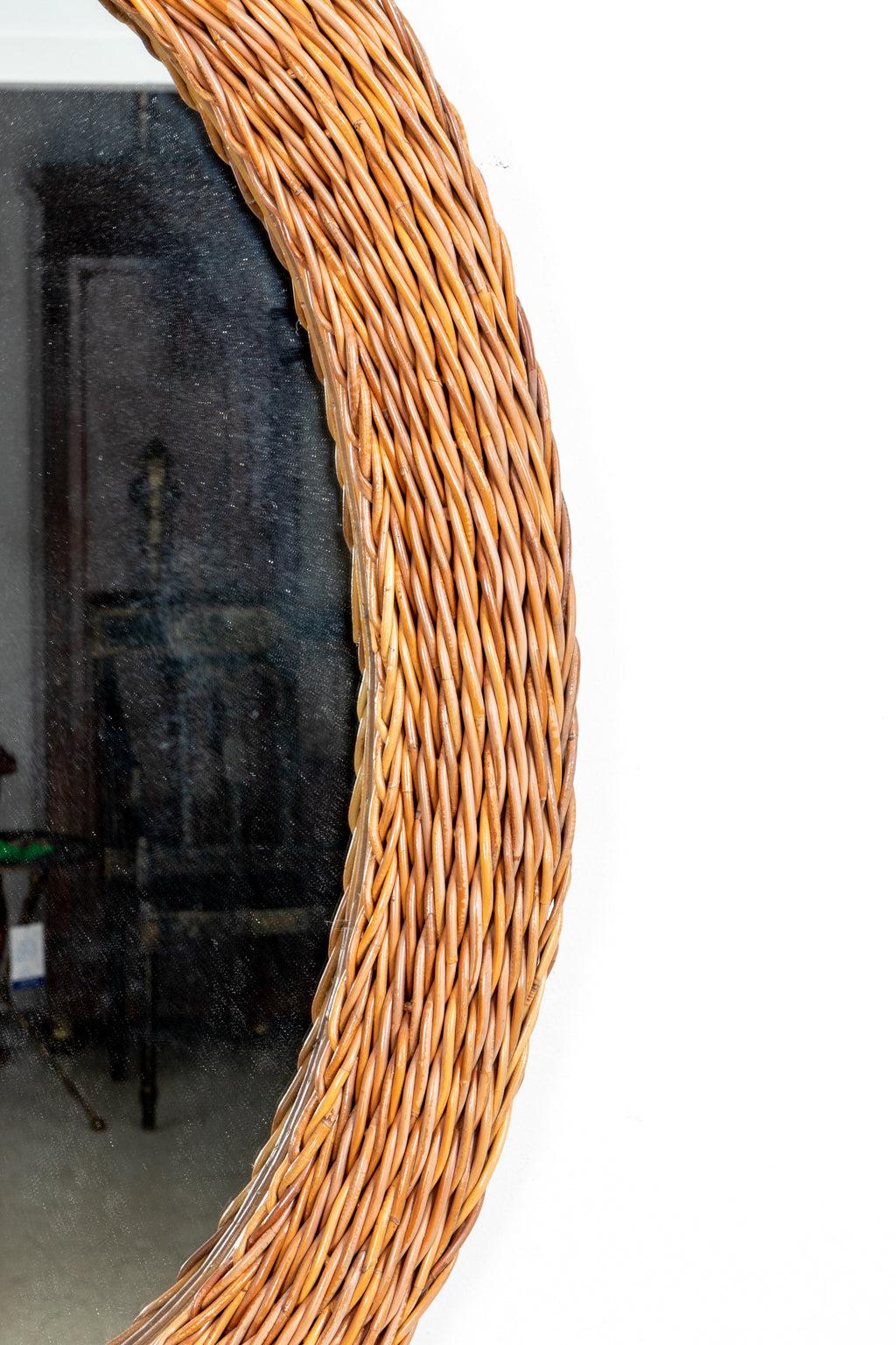 Circa 1970-1990s large oval shaped woven wicker mirror. The mirror can be wired to be hung vertically or horizontally. Origin unknown. Please note of wear consistent with age.
