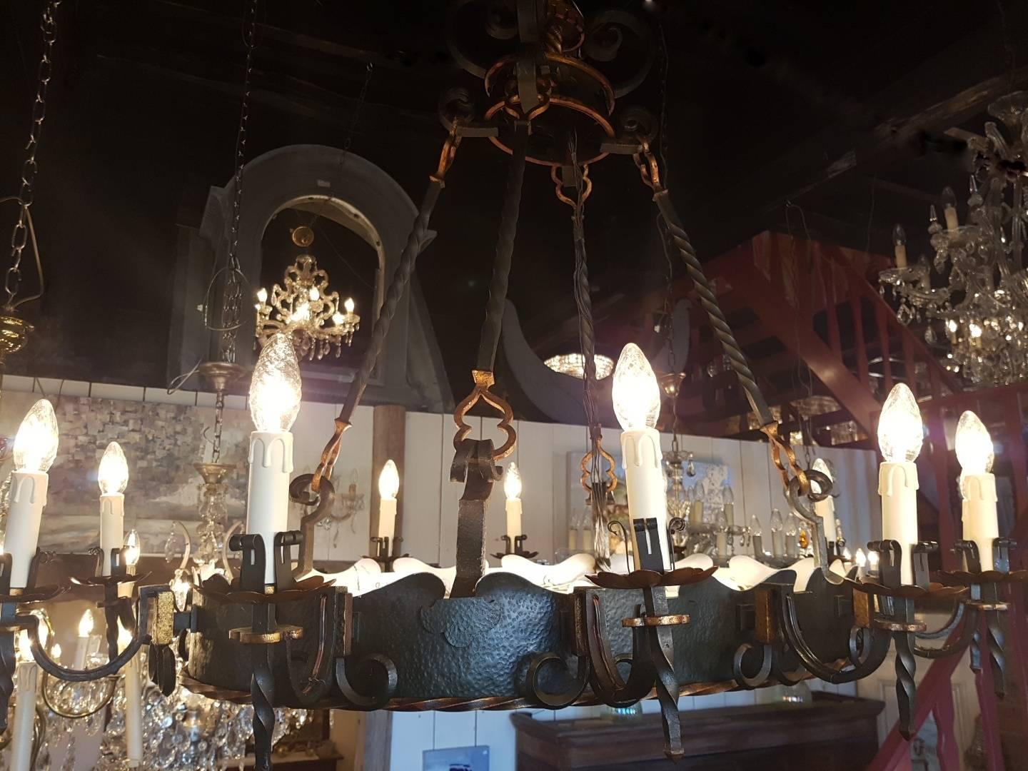 Original oval wrought iron castle chandelier with eight lights at the bottom installed above an oval glass plate. 12 candle lights connected to the ring painted in the colors black and doré /gold. Nicely decorated by the blacksmith with ornaments