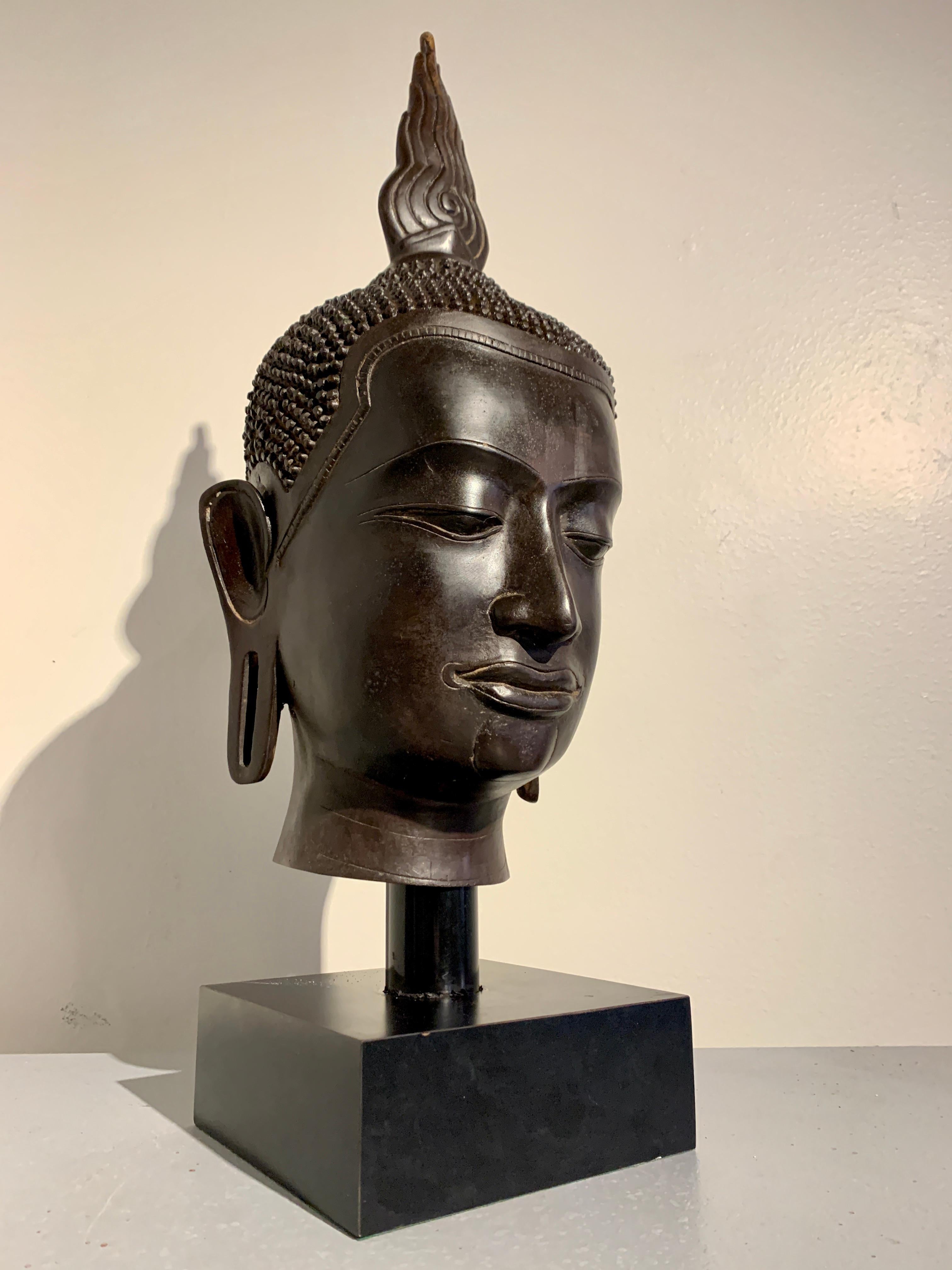 An large and impressive vintage Thai cast bronze Buddha head, U-Thong style, 1970's, Thailand.

The larger than life-sized head beautifully cast with refined details. The Buddha's face is slender, with squared off features. Downcast almond shaped