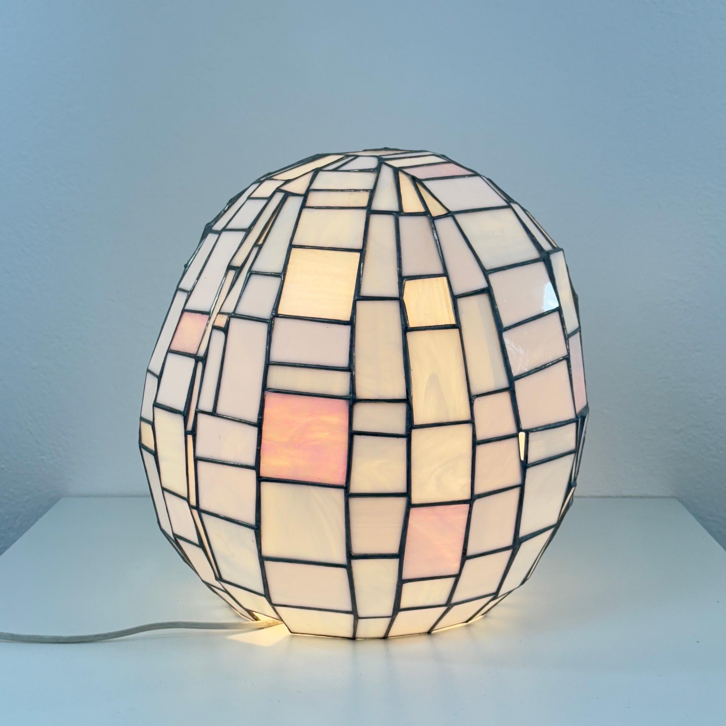 Lampe de table ou lampadaire à la manière de Tiffany, fin du 20e siècle.
Une forme ovoïde sculpturale entièrement réalisée à la main dans une mosaïque de panneaux de verre nacré irisé, chaque pièce étant méticuleusement coupée et assemblée selon la