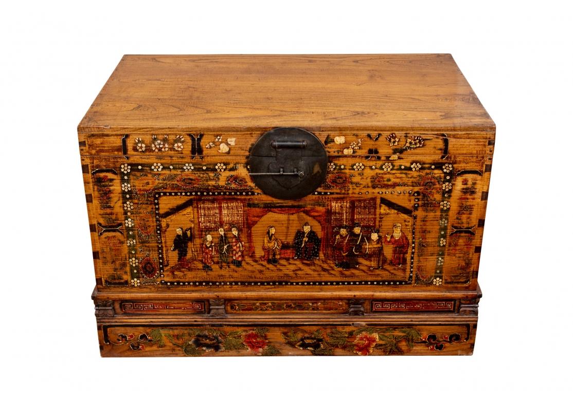 A very decorative and bell made Asian Trunk made from a type of Asian Elm. The chest in an antiqued honey tone stain. The front decorated with a panel with figures in an interior and multiple floral borders, the sides with floral sprays. The
