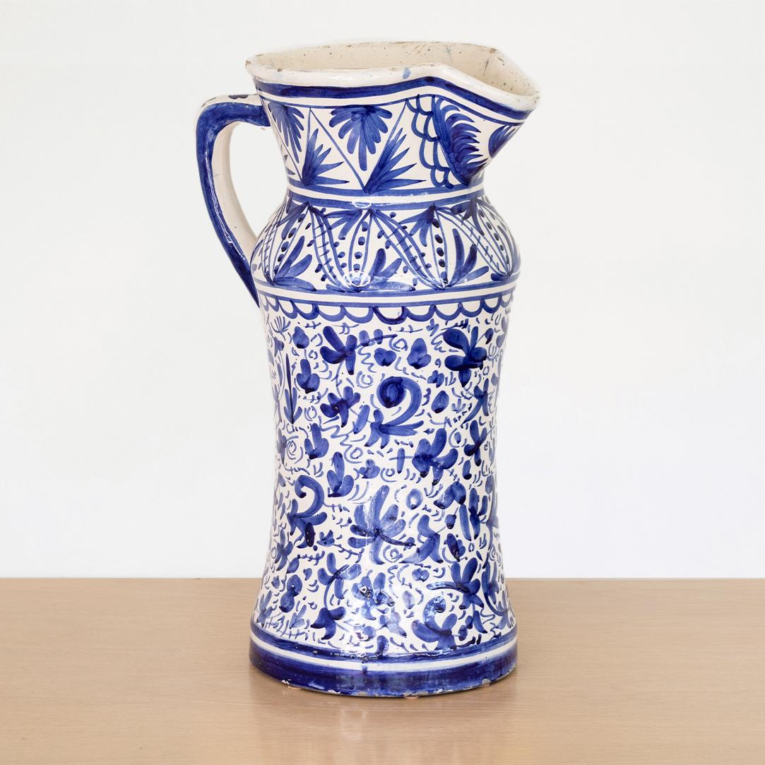 Impressive large size ceramic pitcher from Spain, 1930's. Oversized white glossy pitcher with handle with ornate hand painted motif in a beautiful blue accent color. In the style of Granada ceramics. Unique and eye catching piece. 
 