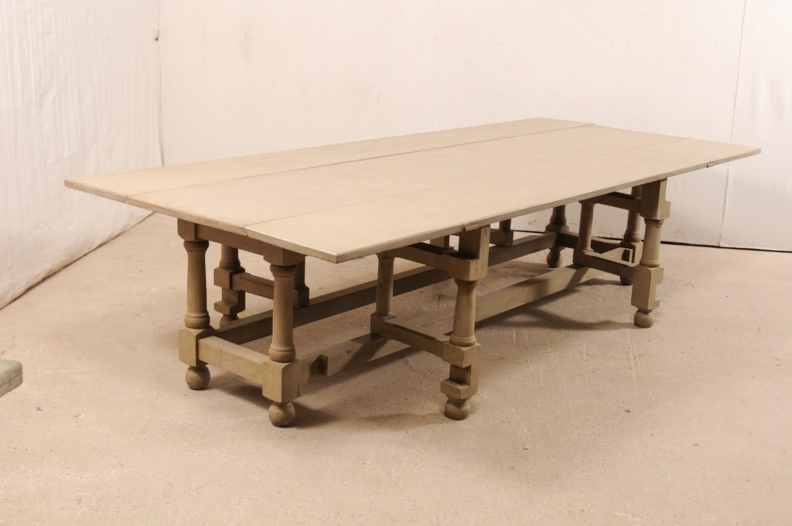 A large-size double gate-leg drop leaf painted American poplar wood table. This vintage American table features a rectangular-shaped top with two drop leaf sides, and a double set of gate legs. The baluster style legs are supported with a box