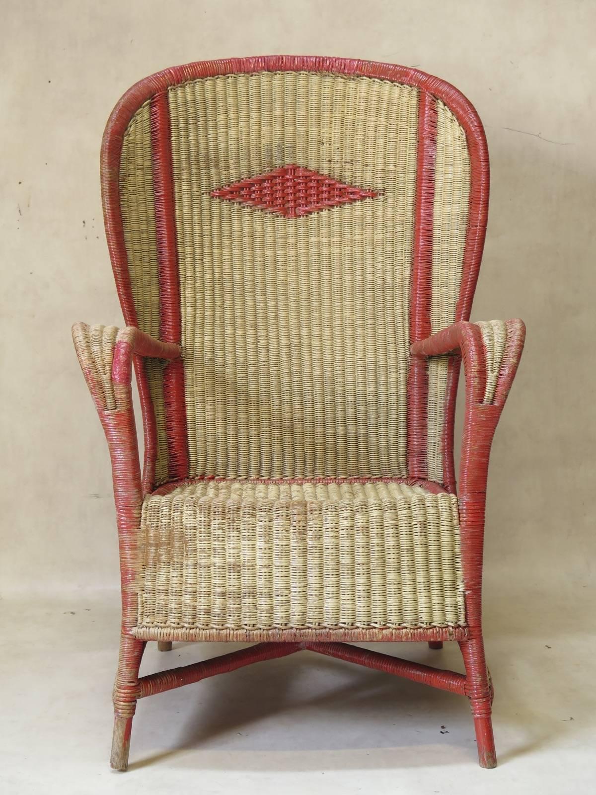 Unusual and very large wingback chair, of tightly-woven, fine wicker, with a tall, rounded back, painted cream and red. Diamond-shaped detail in the back.