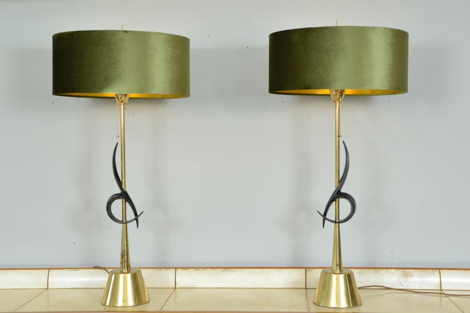 A spectacular pair of large table lamps designed and manufactured by the Rembrandt Lamp Company of Chicago. Standing nearly a metre tall, these impressive and super glamorous lamps with dark green velvet drum shades, are classic American Mid-Century