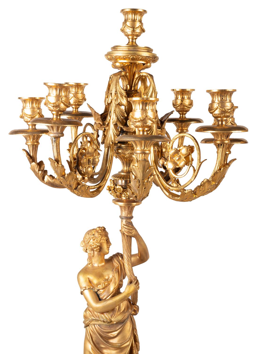 A large and impressive pair of 19th Century classical gilded ormolu and white marble candelabra. Each with scrolling foliate seven branch sconces, supported by maidens dressed in flowing gowns and vine leaves in the hair, raised on circular white