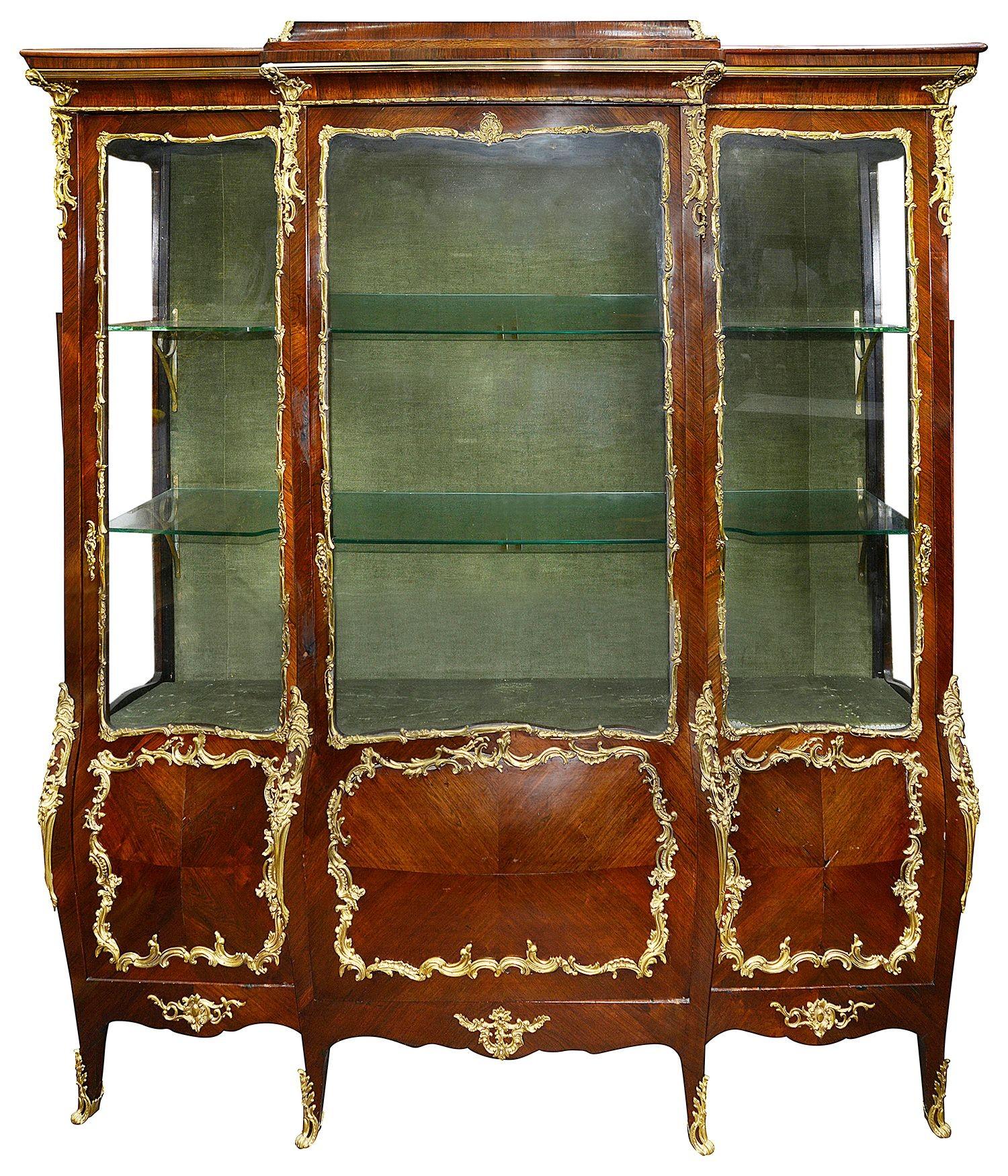 A good quality pair of French Louis XVI style break fronted, Rococo style ormolu mounted vitrines, each with adjustable shelves, three glazed doors to each, with storage behind the bombe fronted panelled section below, raised on elegany out swept,