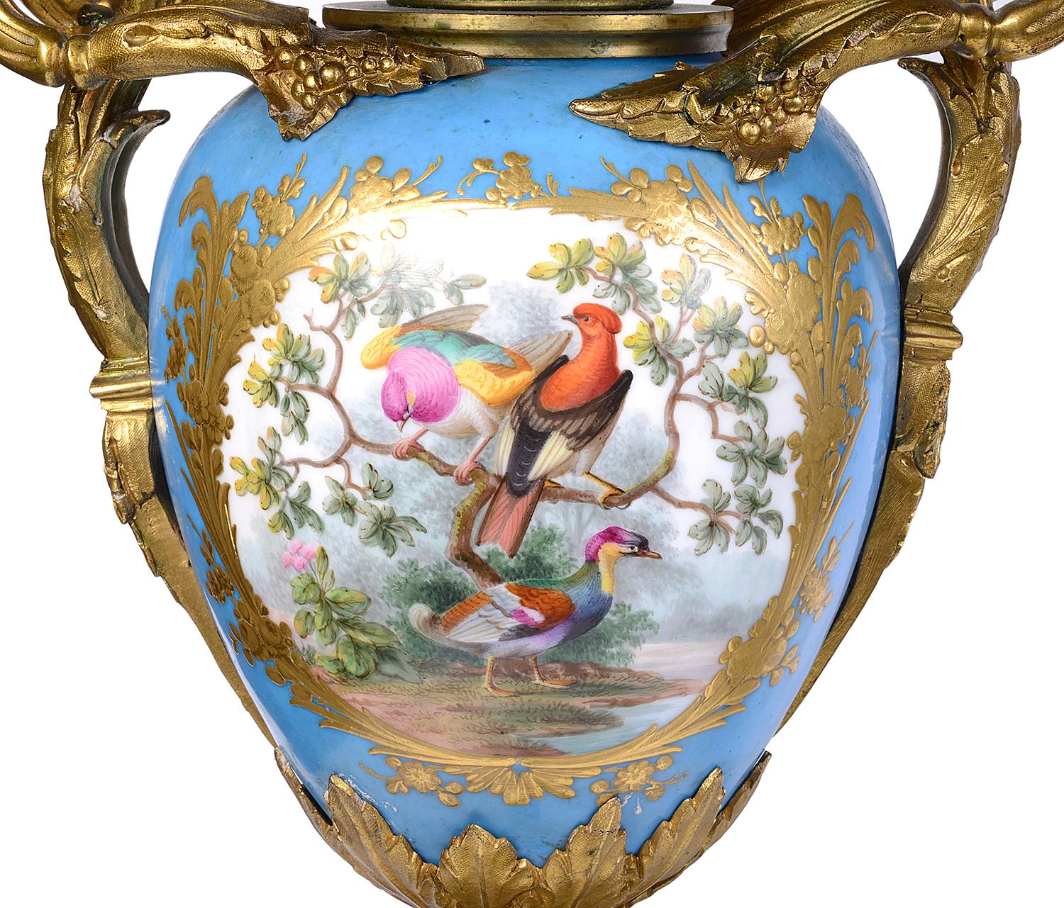 A very good quality pair of 19th century French Sevres style porcelain and gilded ormolu candelabra, each having five scrolling foliate branch sconces coming off the turquoise ground porcelain, with painted central panels depicting exotic birds in